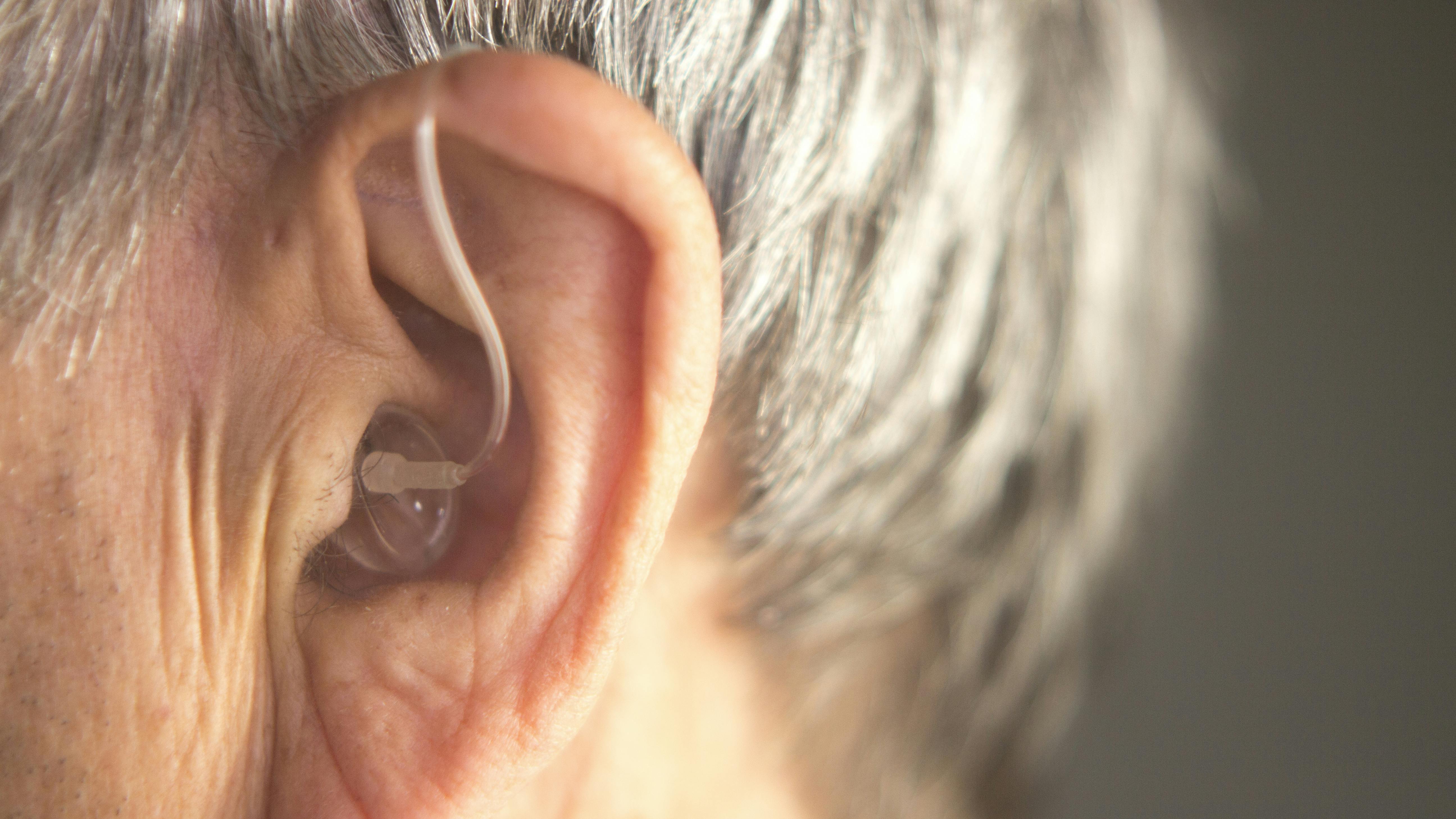 Digital modern hearing aid in the ear of aged old man.