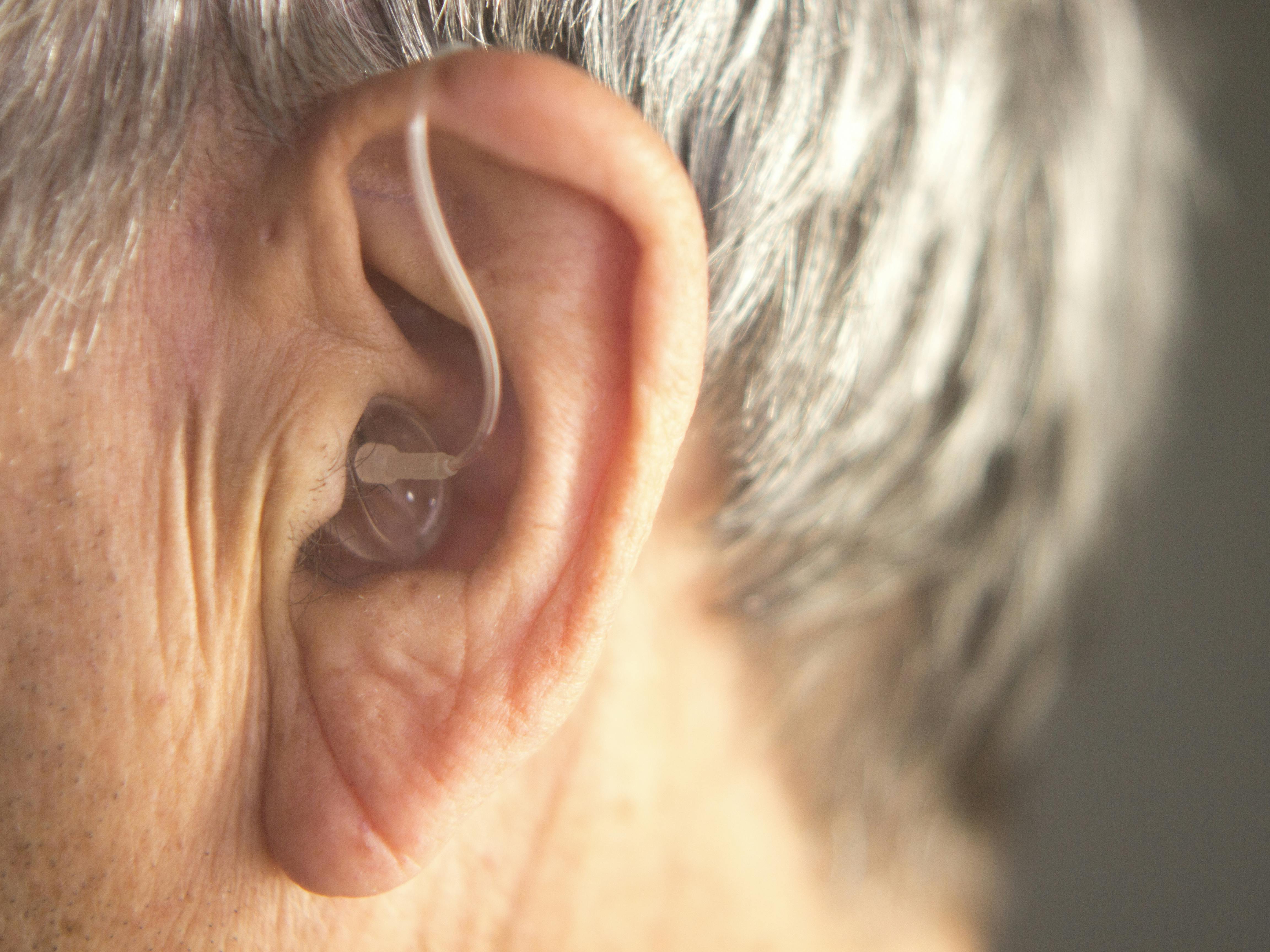 Digital modern hearing aid in the ear of aged old man.