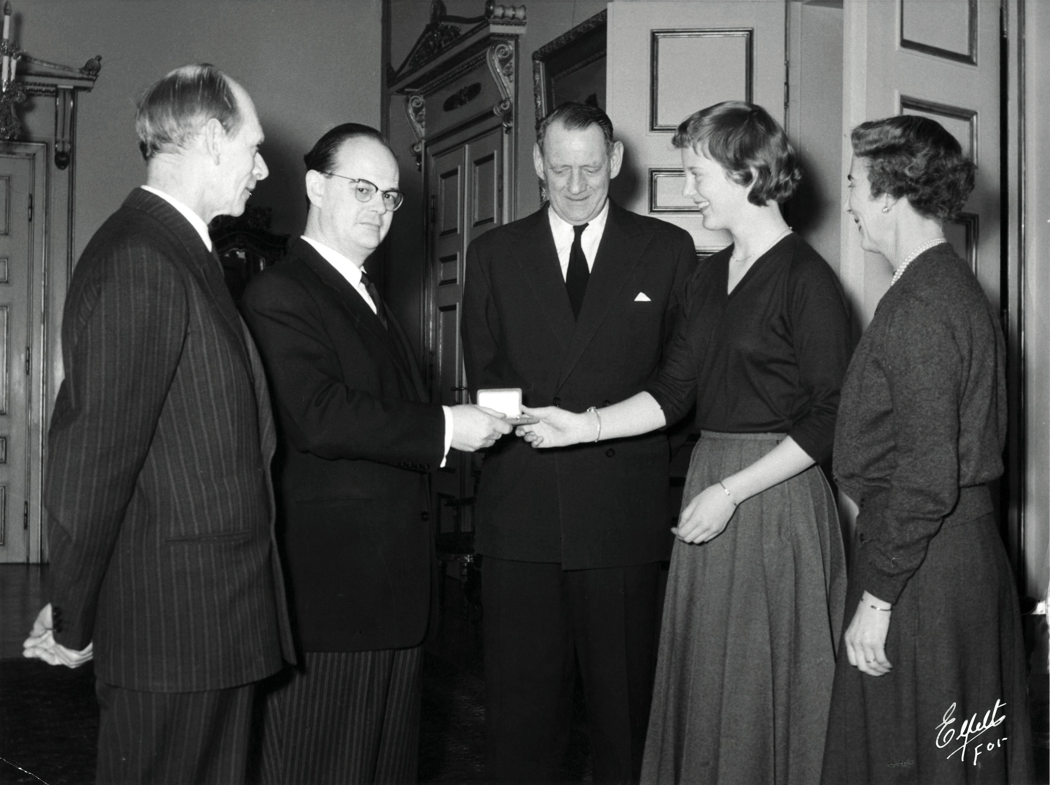 Tronfølger Margrethe fylder 18-års fødselsdag den 16. april 1958, og i den anledning bliver den første mønt med prinsessens portræt slået. Mønten overrækkes af finansminister Viggo Kampmann (nr. to fra venstre). Udateret arkivbillede fra 1958.