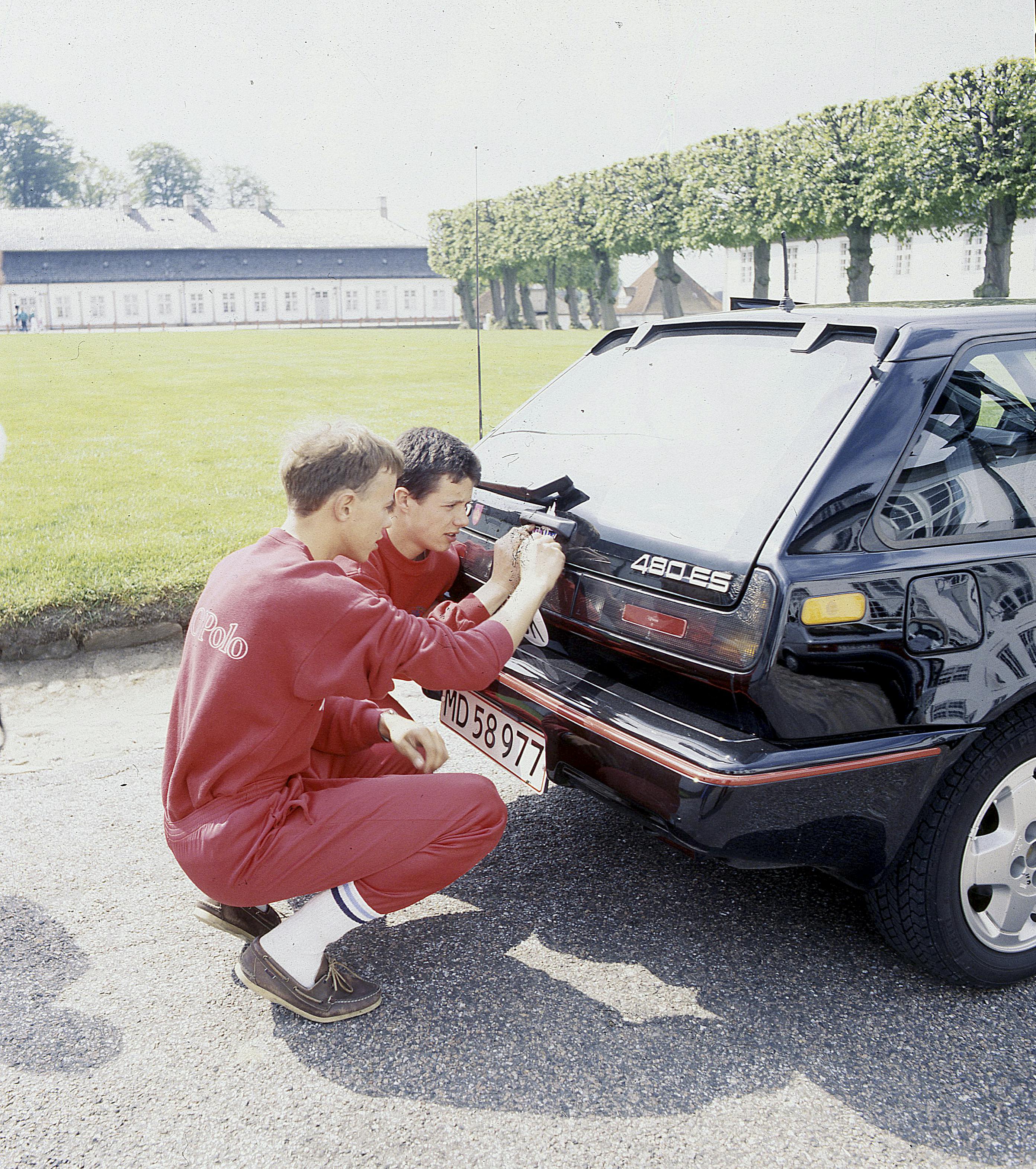 Kronprins Frederik har altid elsket hurtige biler. Her ses han sammen med prins Joachim på hug bag kronprinsens Volvo 480 Turbo ved Fredensborg Slot.