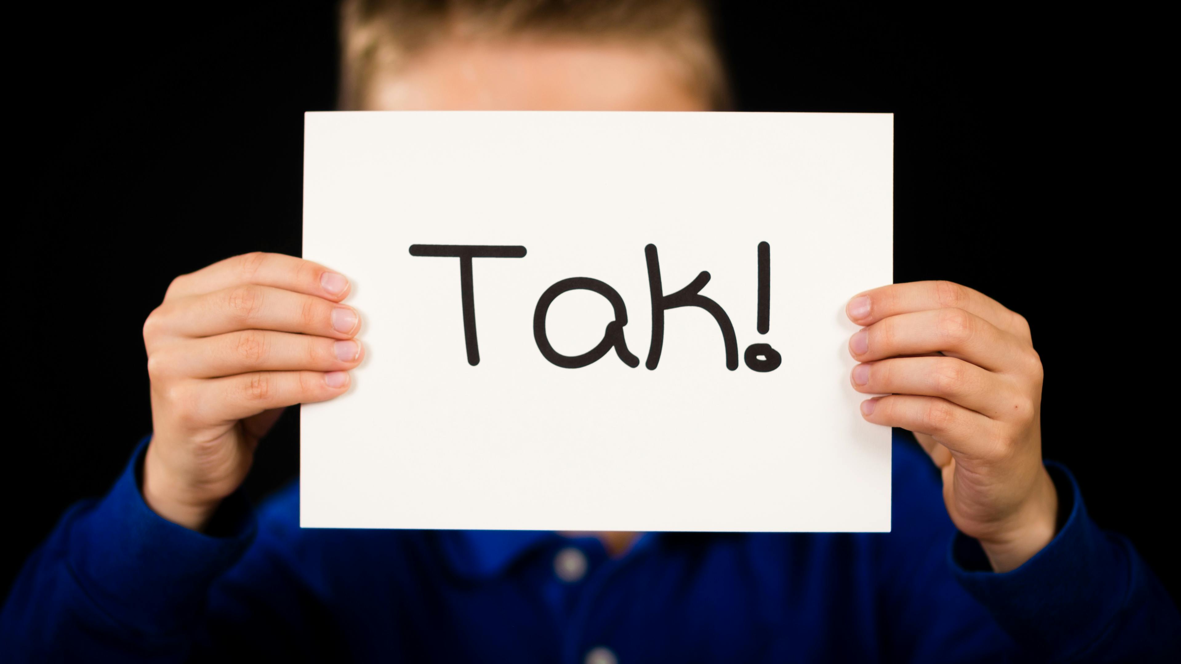 Et barn holder et skilt, hvor der står tak