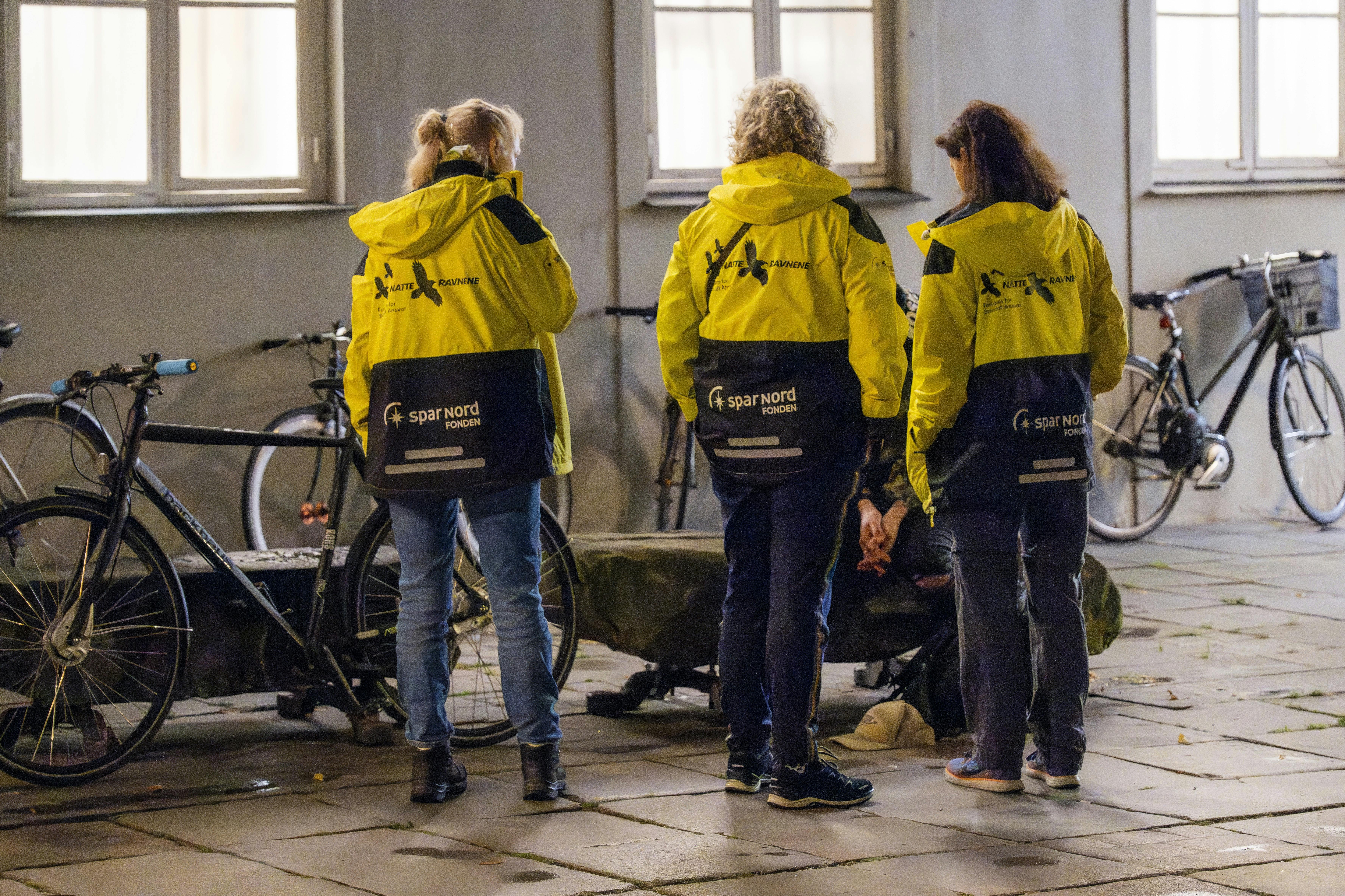 Tre kvinder fra Natteravnene står omkring en ung mand