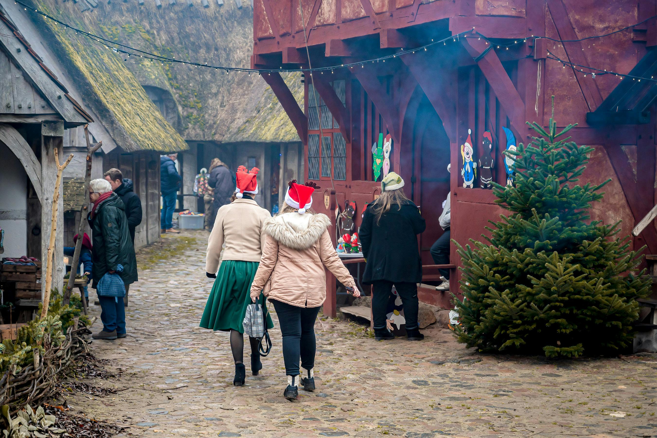 Kvinder med nissehuer går rundt på julemarked