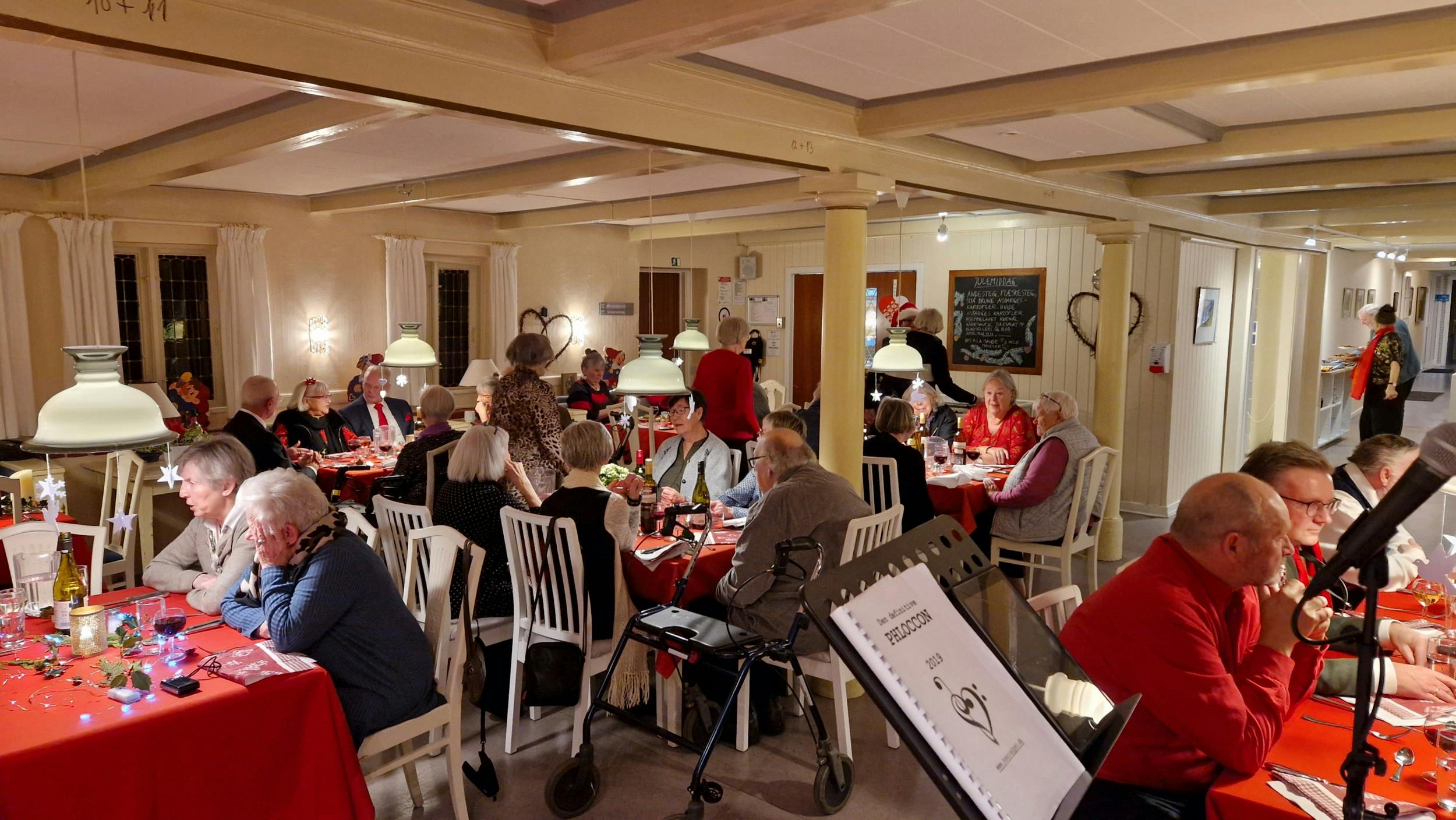 Julemiddagen serveres ved borde, som kursisterne selv dækker. Liss og Jørgen sidder sammen med vennepar, de tidligere har mødt på højskolen.