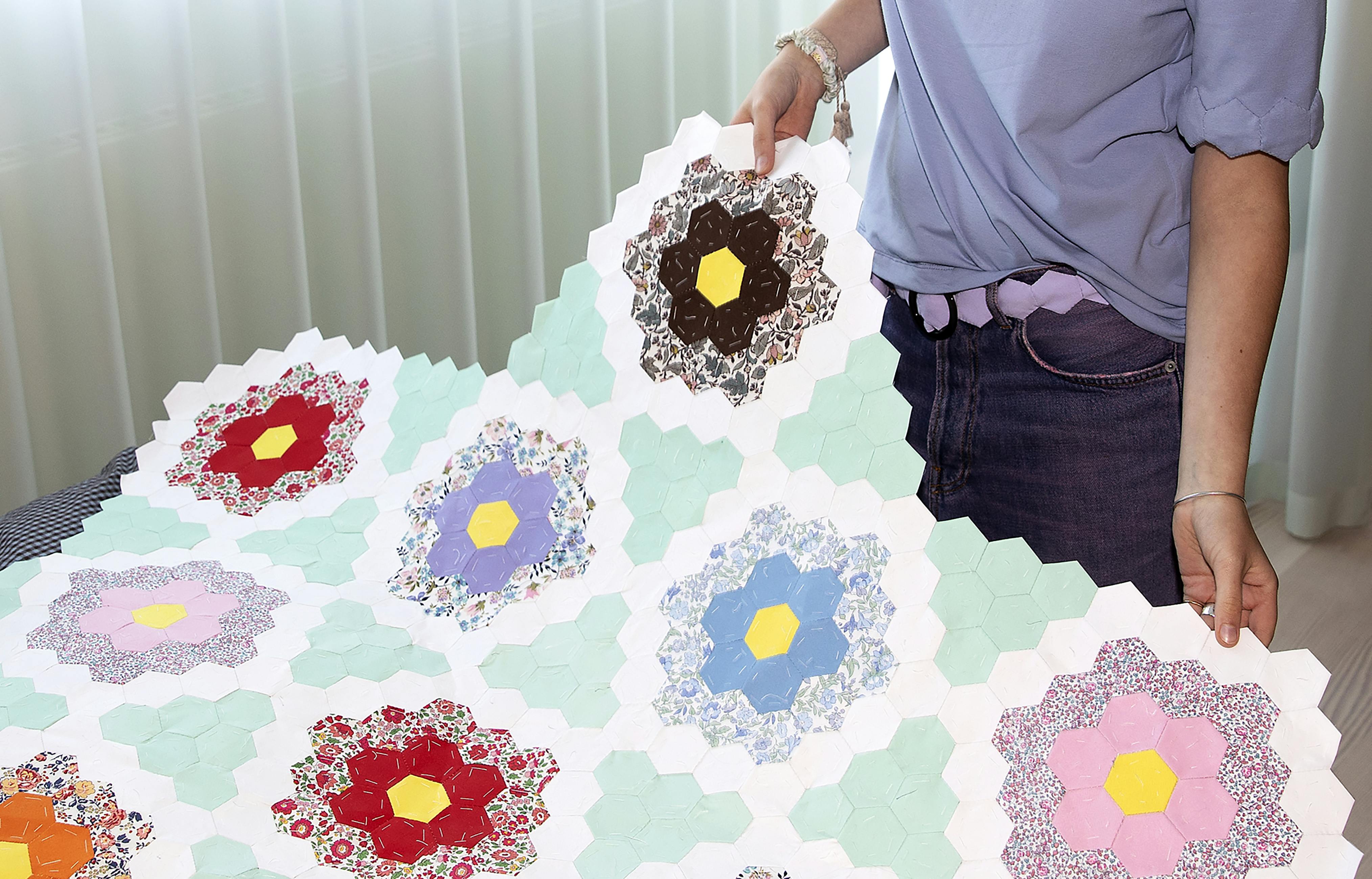 Dette patchworktæppe har Emma syet i hånden. Bagpå sidder stadig papskabelonerne, som skal pilles ud en efter en. Det kræver tid og tålmodighed at sy sådan et tæppe.