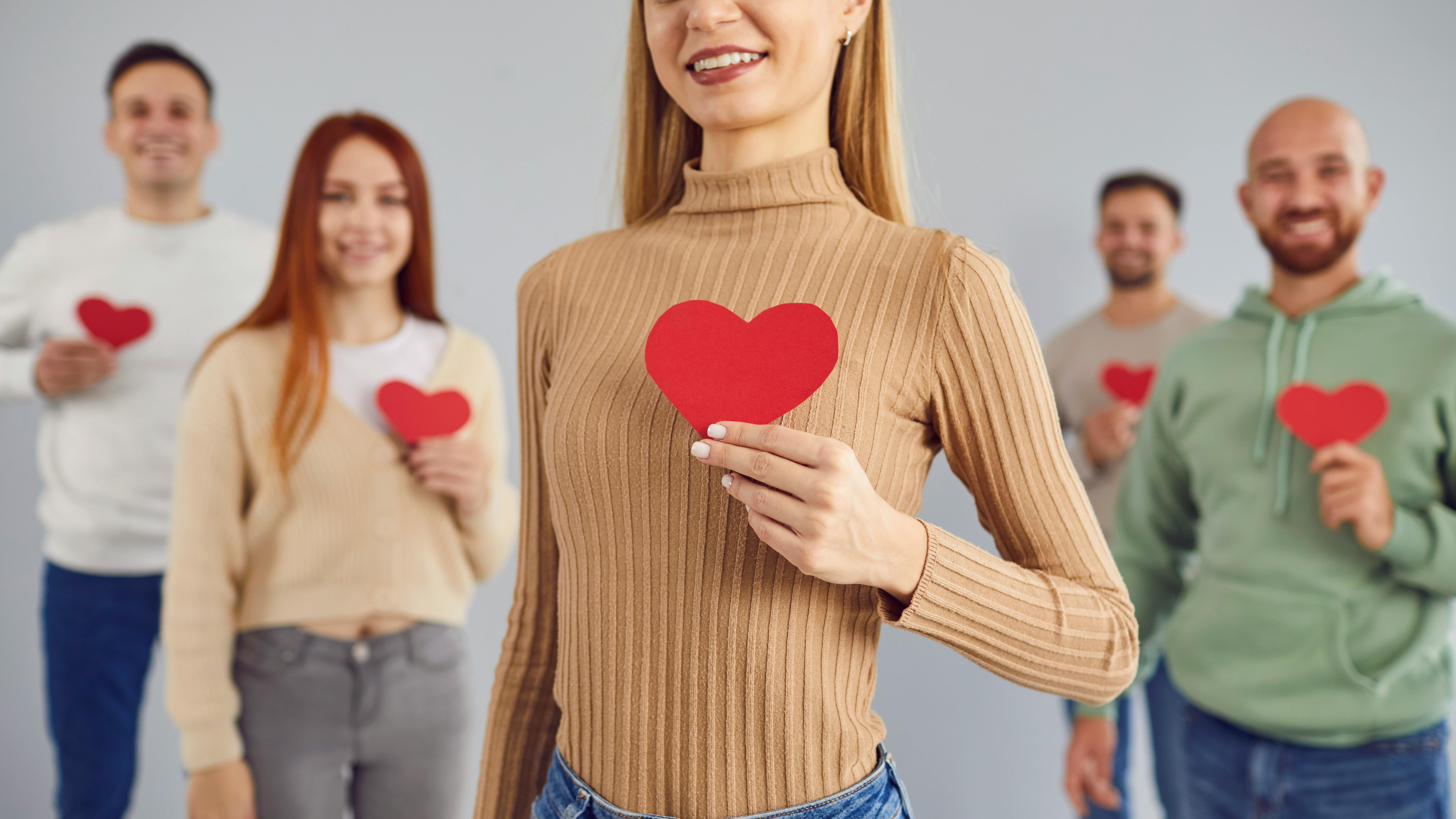 Personer, der holder et rødt hjerte foran sig