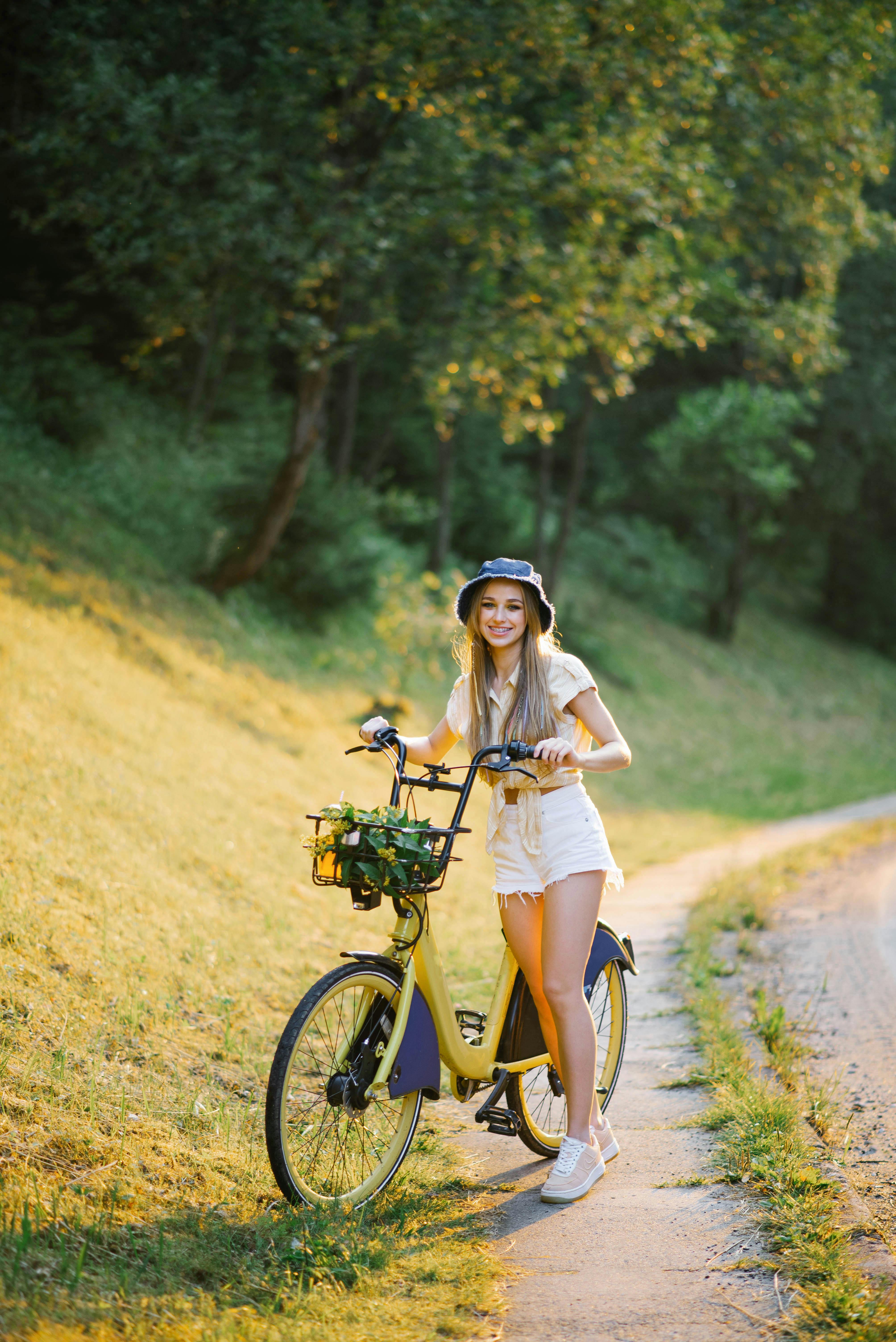 Kvinde står med sin cykel i naturen