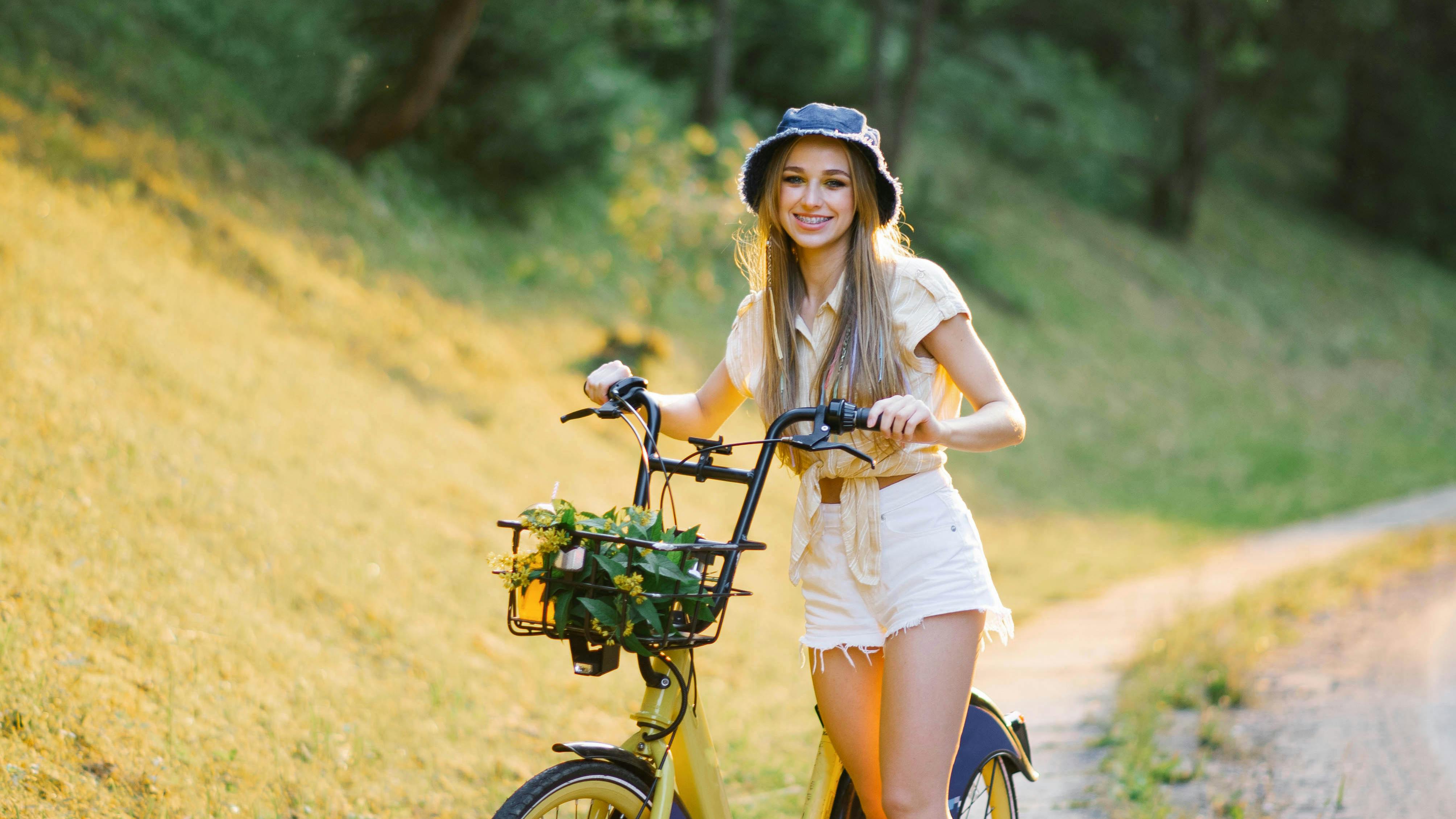 Kvinde står med sin cykel i naturen
