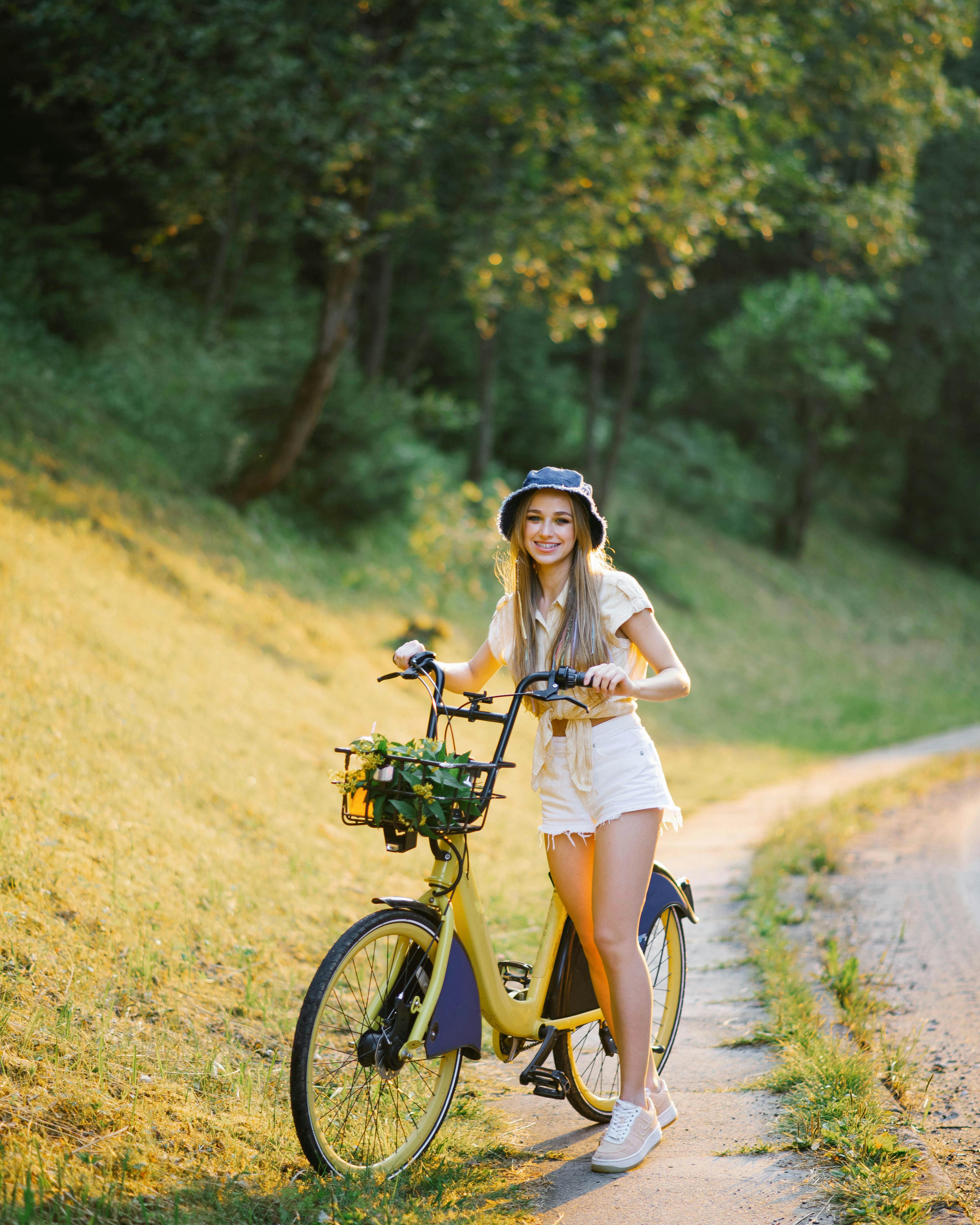 Kvinde står med sin cykel i naturen