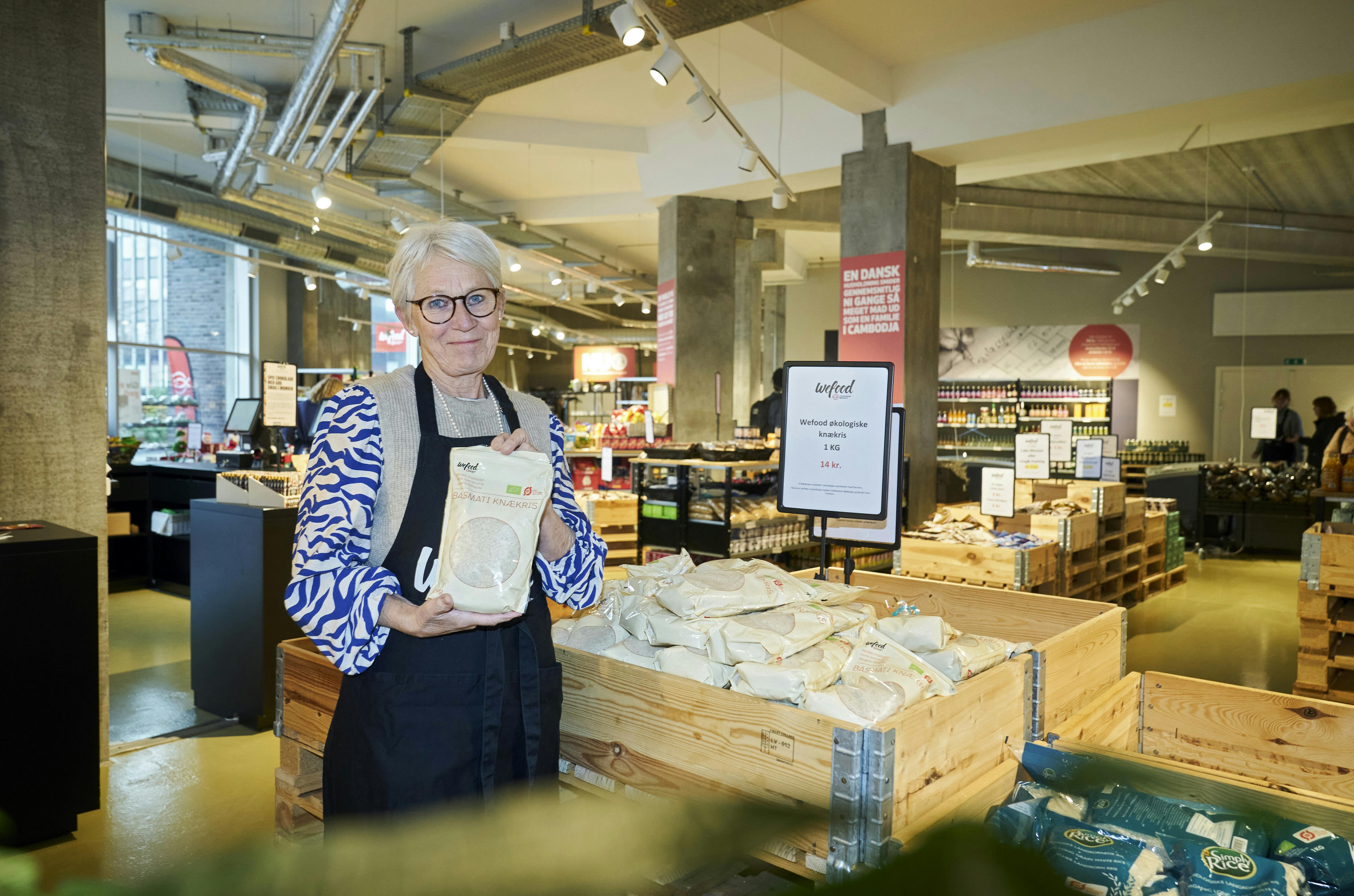 Jane Hurup i WeFood-butikkken i Aalborg, hvor hun lægger mange frivillige arbejdstimer. Posen med knækris - knækkede ris - er WeFoods eget produkt.