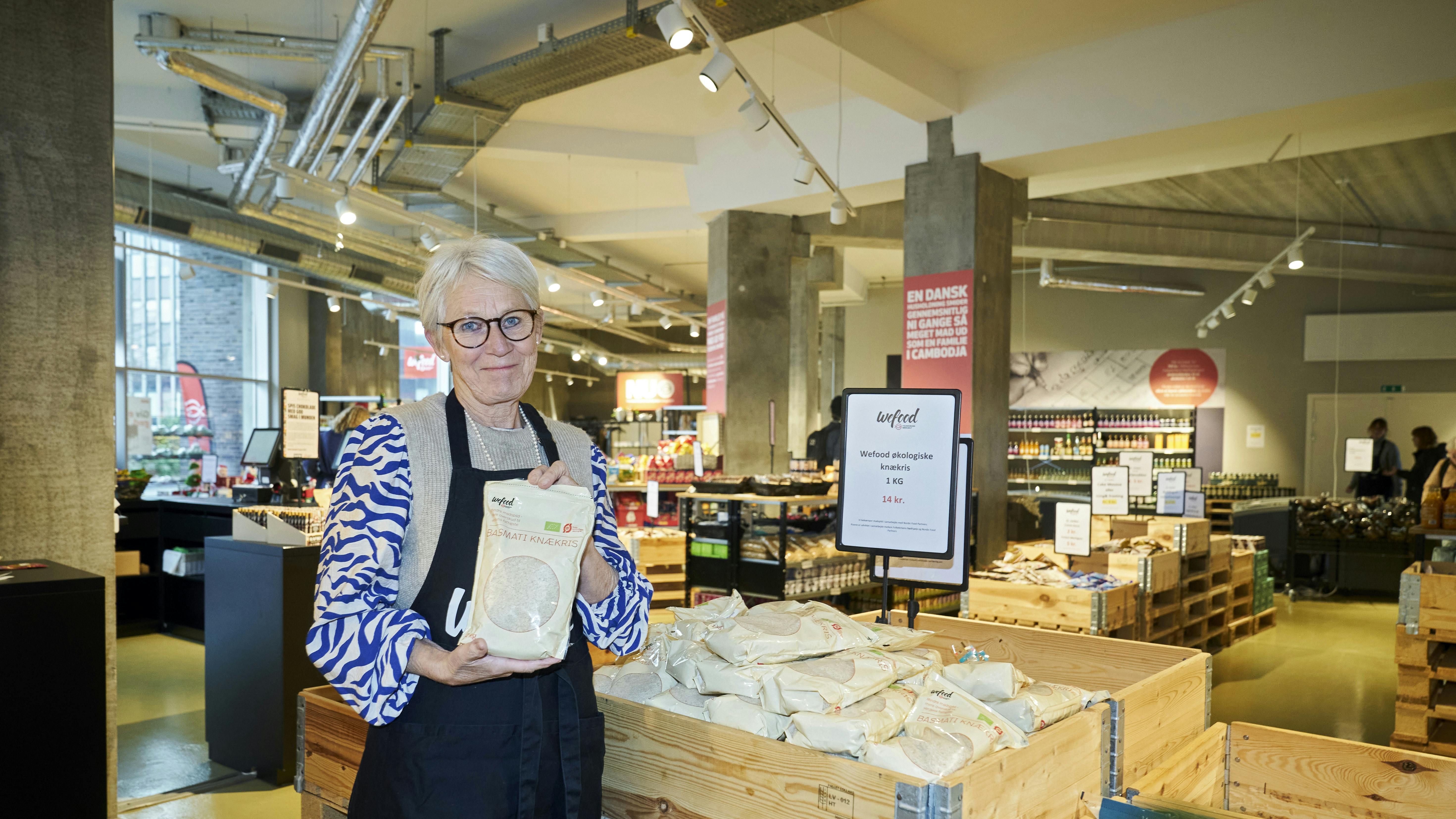 Jane Hurup i WeFood-butikkken i Aalborg, hvor hun lægger mange frivillige arbejdstimer. Posen med knækris - knækkede ris - er WeFoods eget produkt.