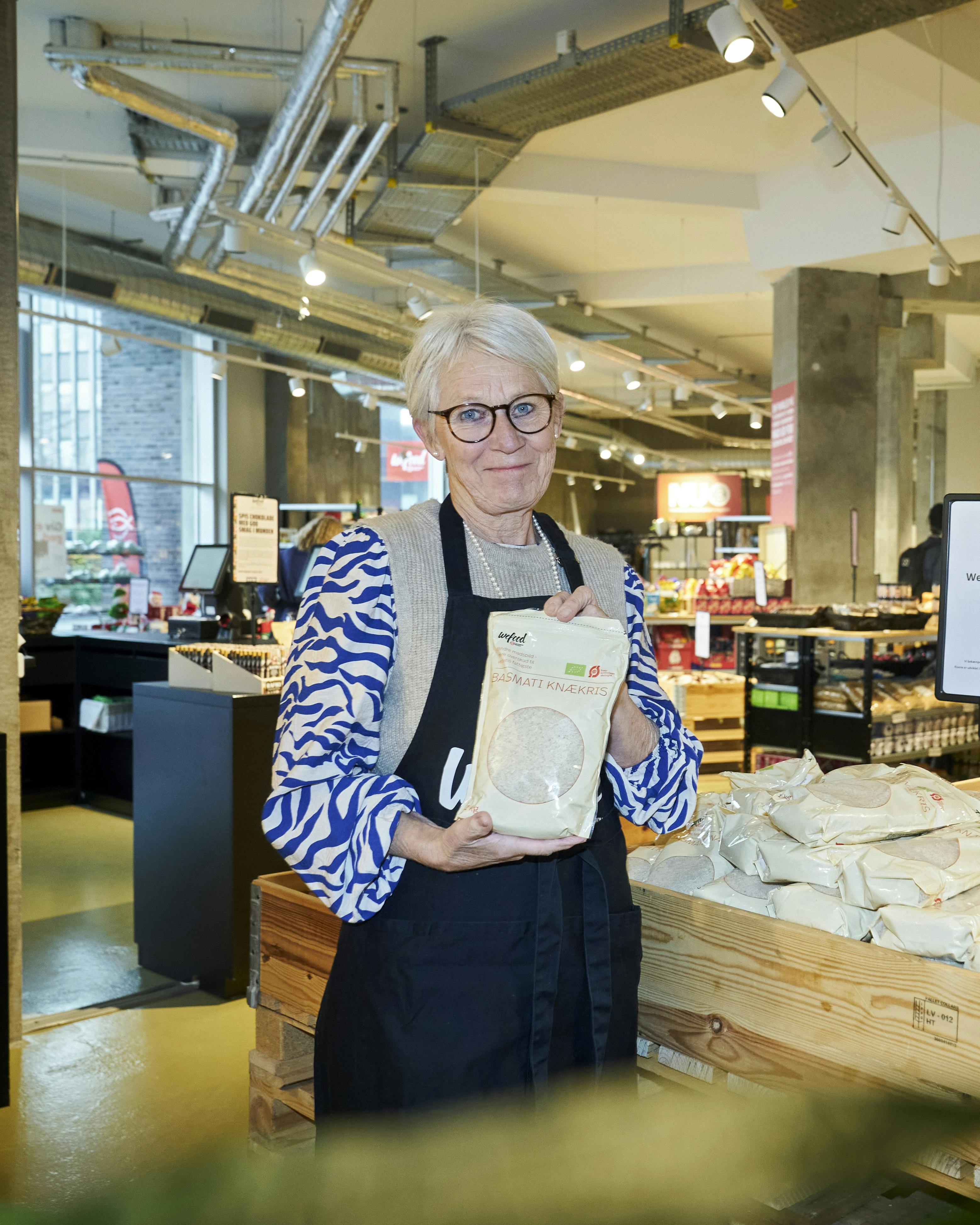 Jane Hurup i WeFood-butikkken i Aalborg, hvor hun lægger mange frivillige arbejdstimer. Posen med knækris - knækkede ris - er WeFoods eget produkt.