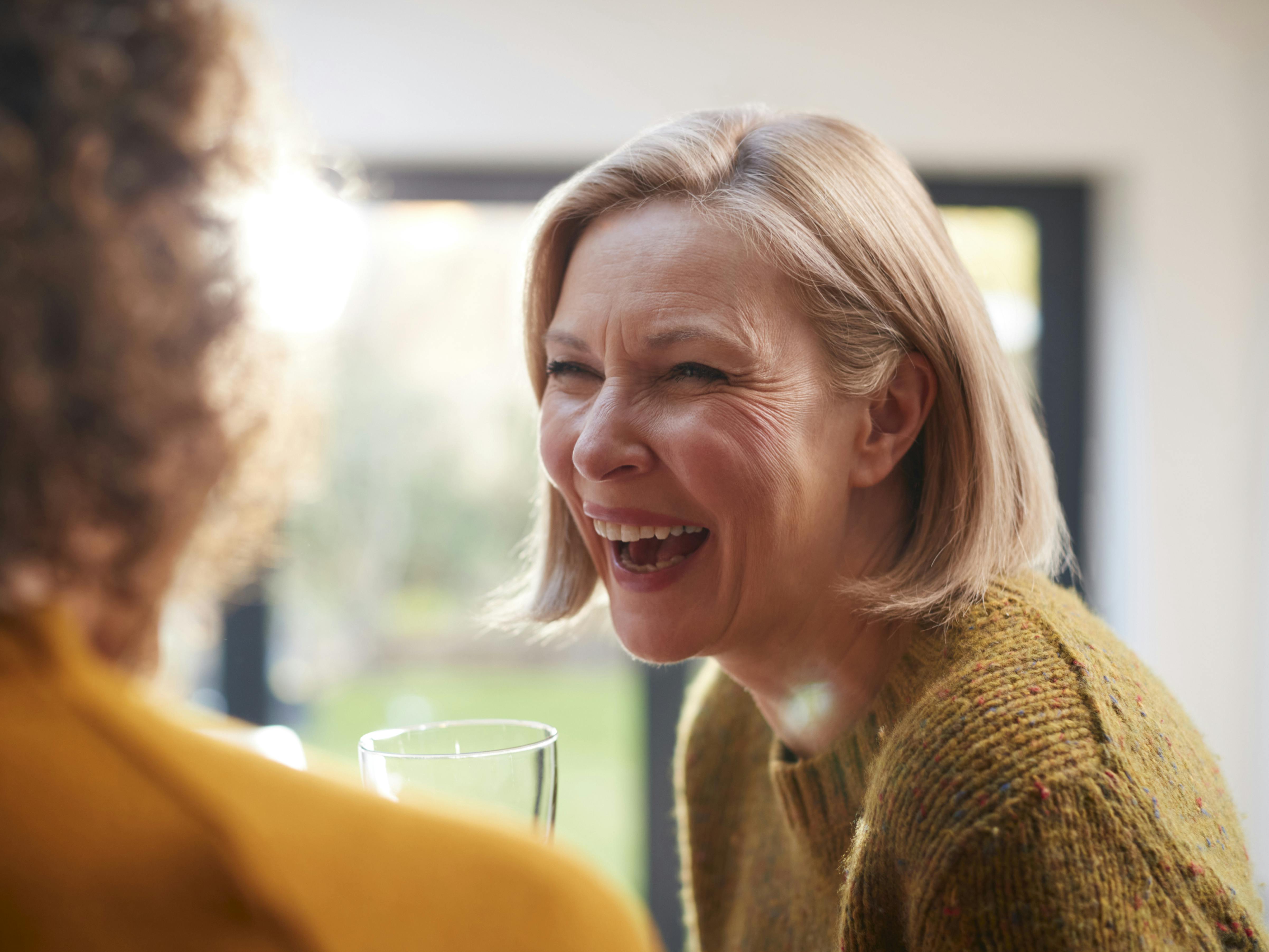 Two Mature Female Friends Meeting At Home To Talk And Drink Wine Together