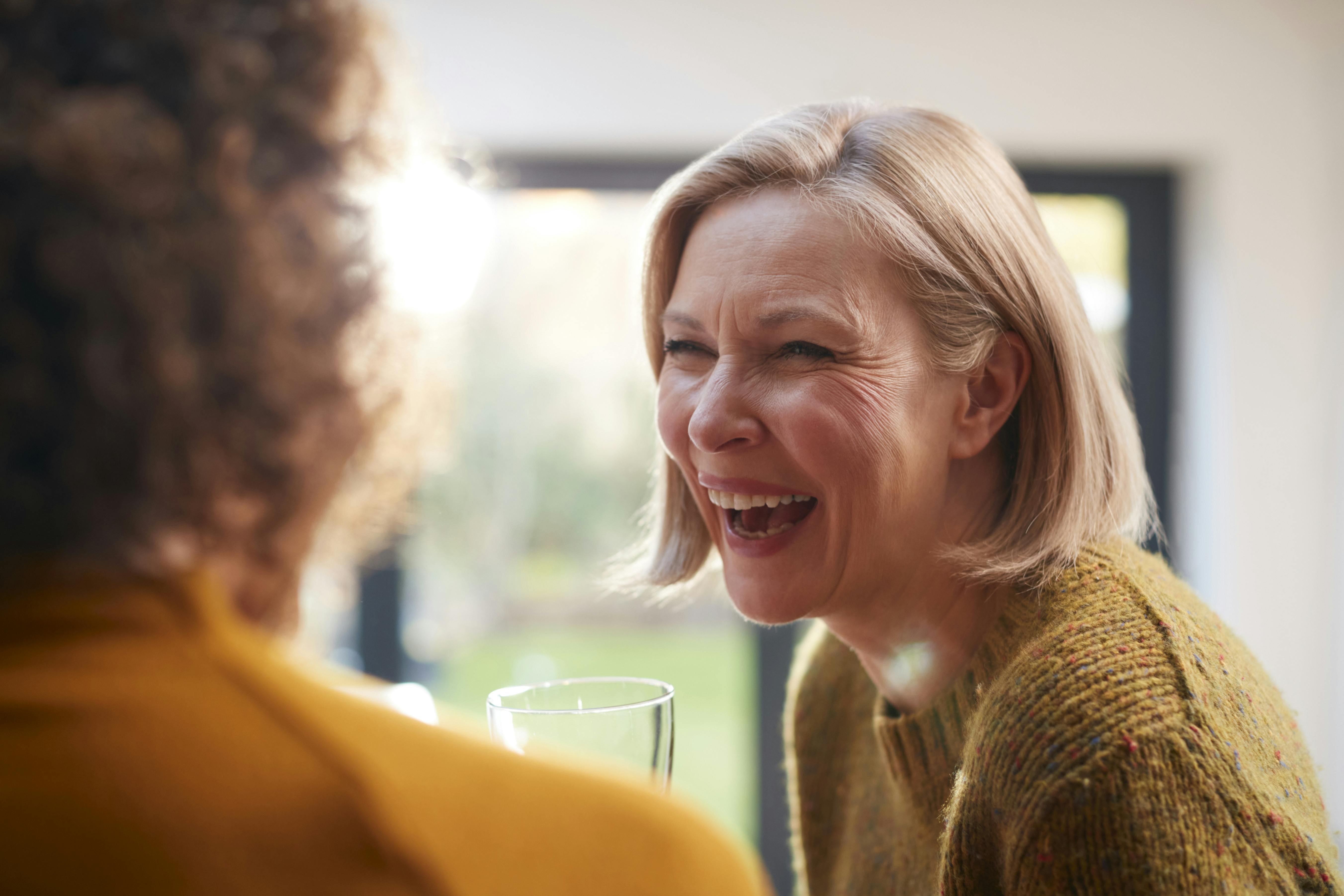 Two Mature Female Friends Meeting At Home To Talk And Drink Wine Together