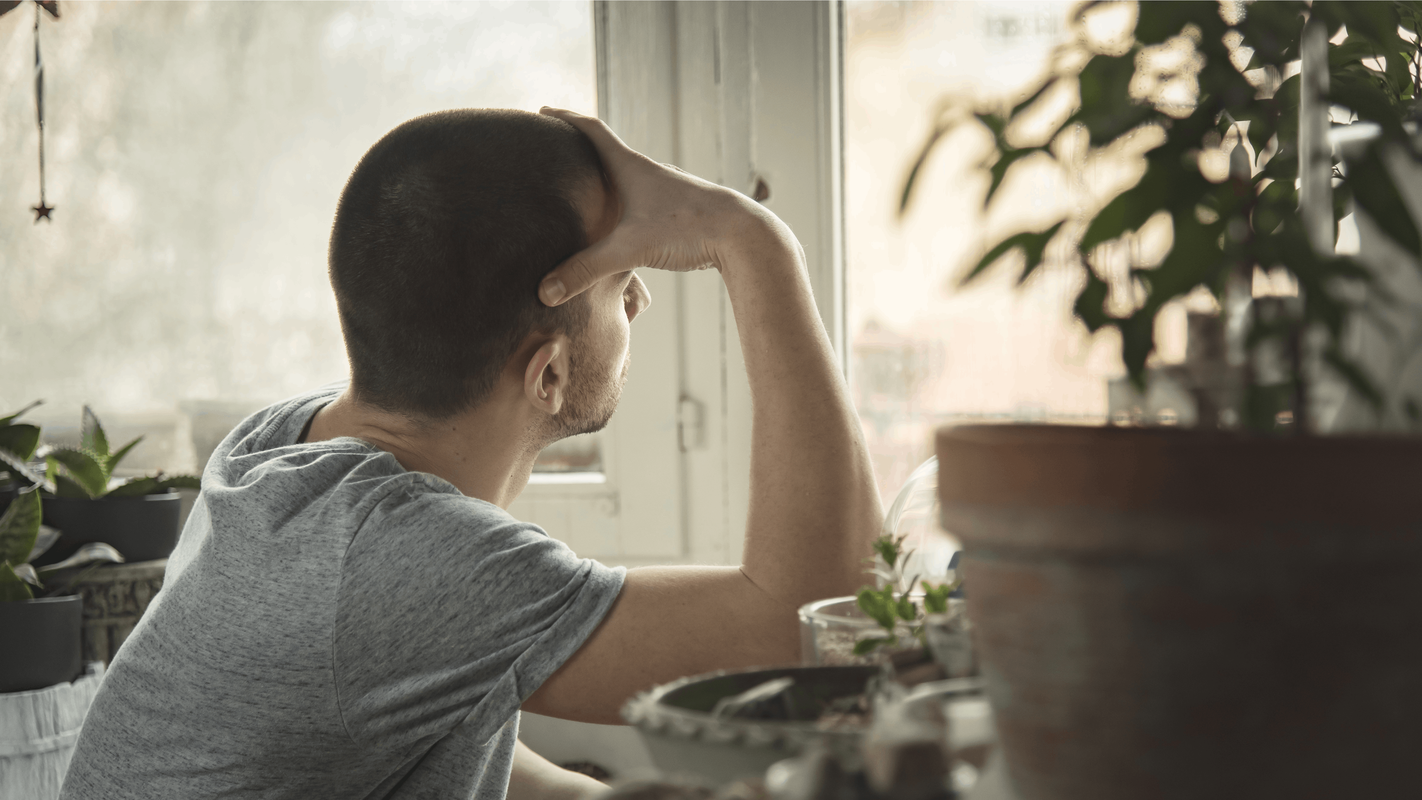 Trist mand kigger opgivende ud af vinduet