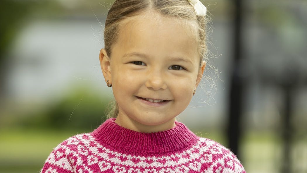 Lille pige med sweater med små hjerter på.