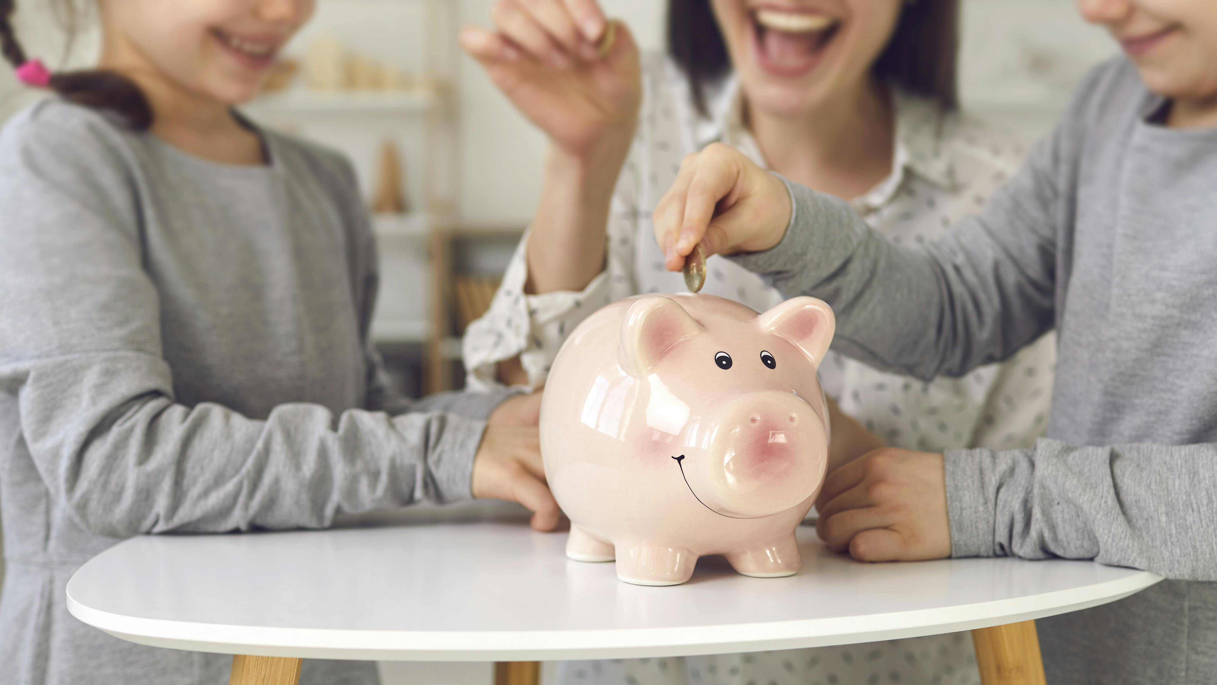 En mor putter penge i en sparegris med sine to børn