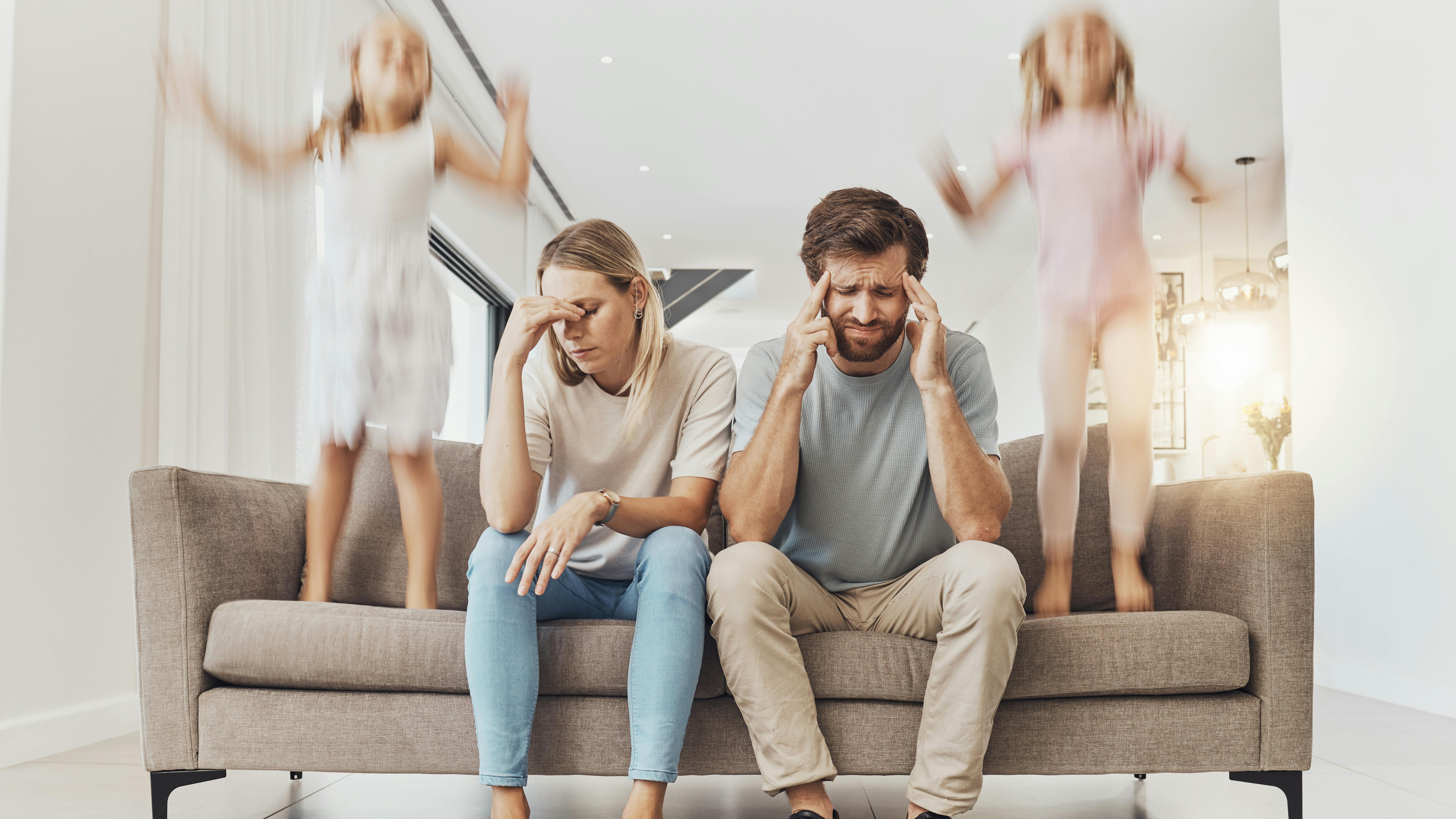 Frustrerede forældre sidder i sofa med børn, der hopper i sofaen