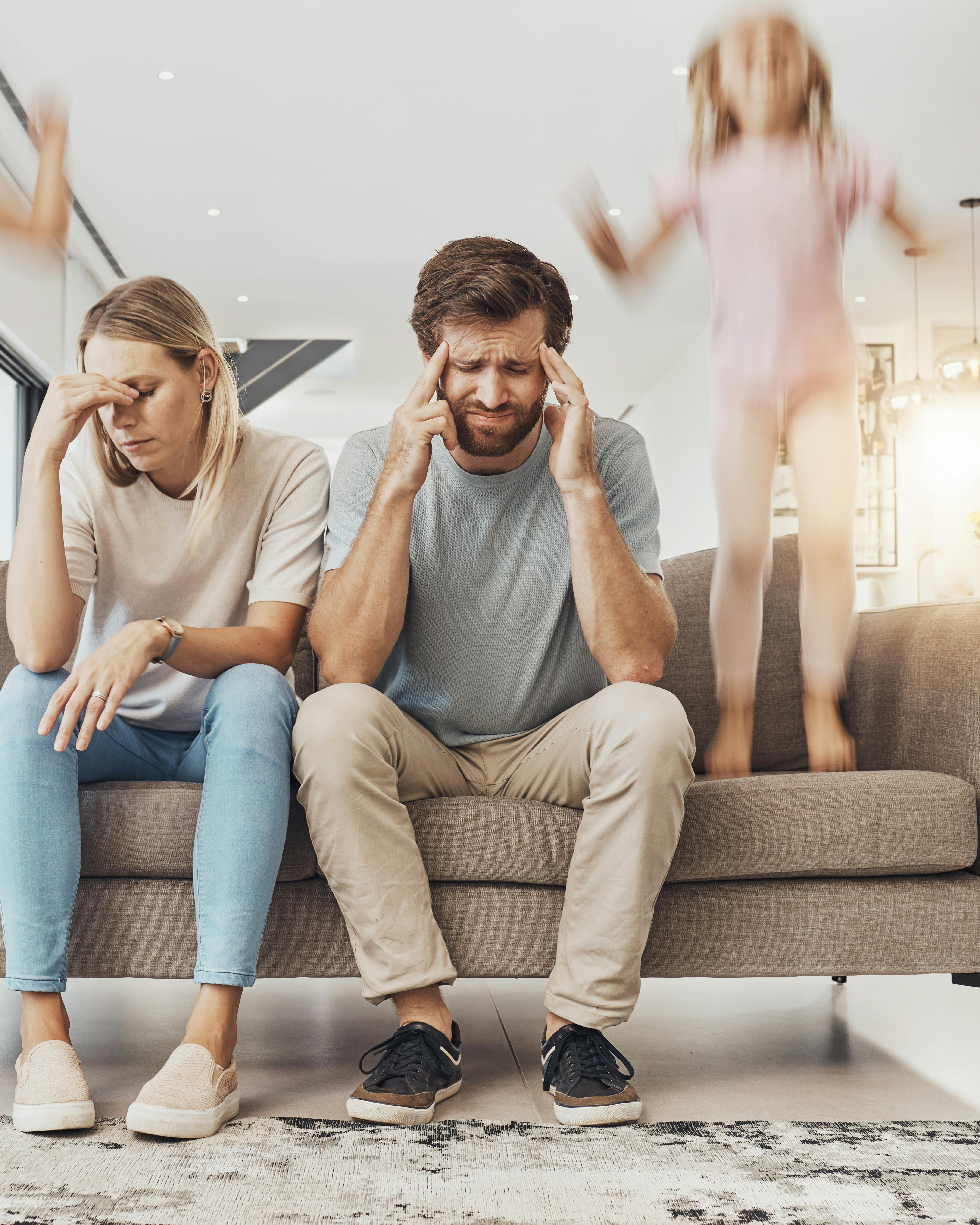 Frustrerede forældre sidder i sofa med børn, der hopper i sofaen