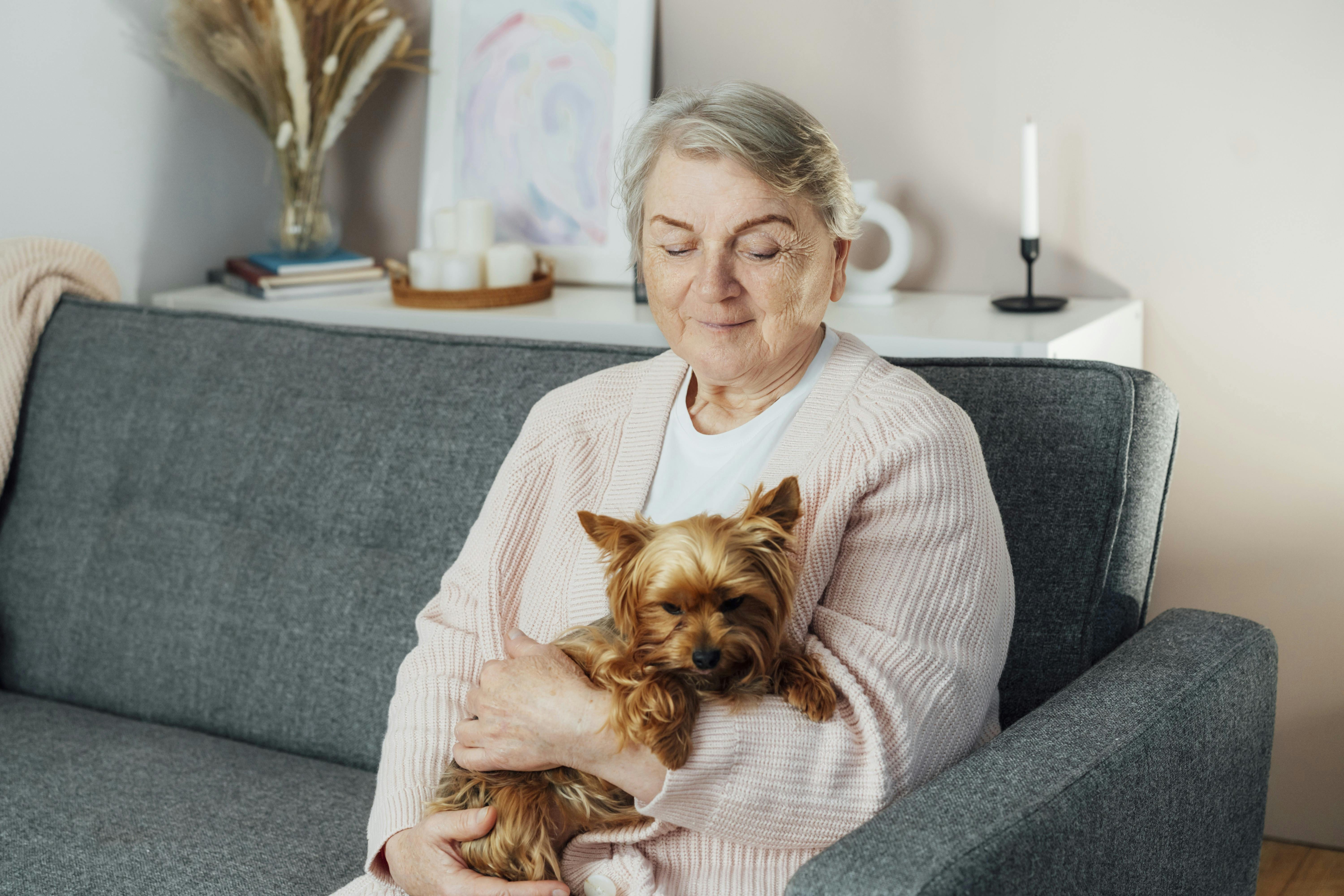 Ældre kvinde sidder med sin hund på skødet