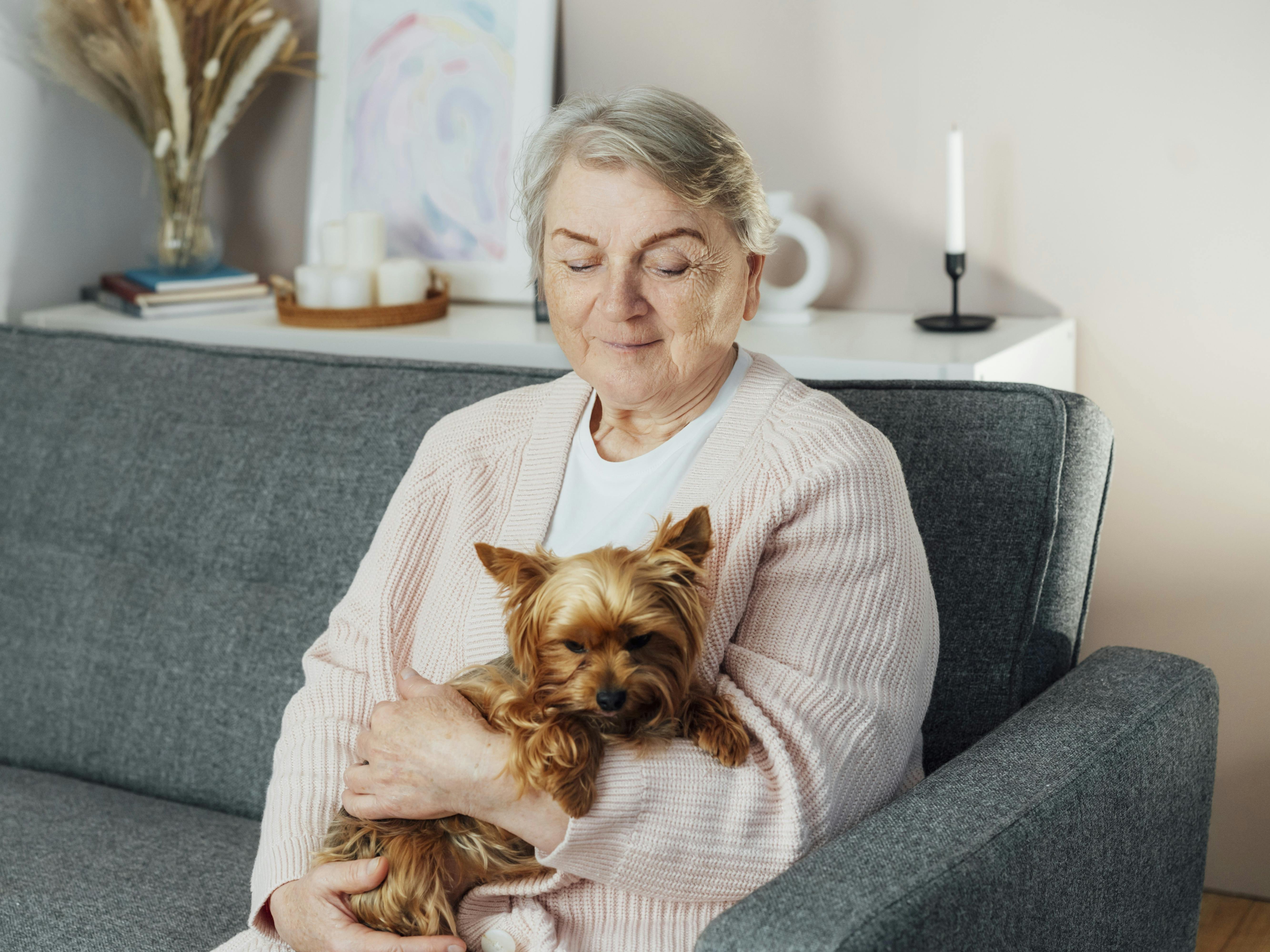 Ældre kvinde sidder med sin hund på skødet