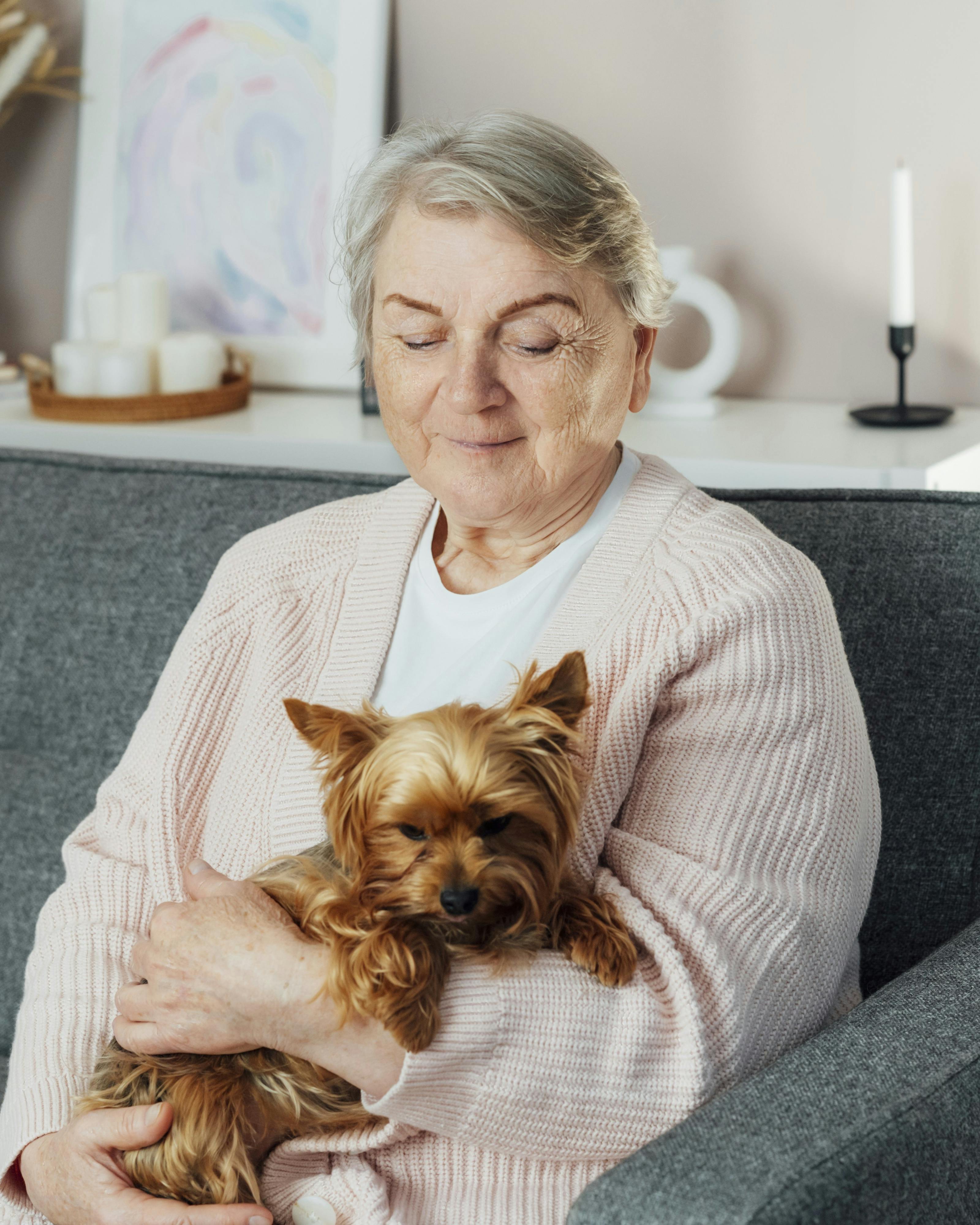 Ældre kvinde sidder med sin hund på skødet