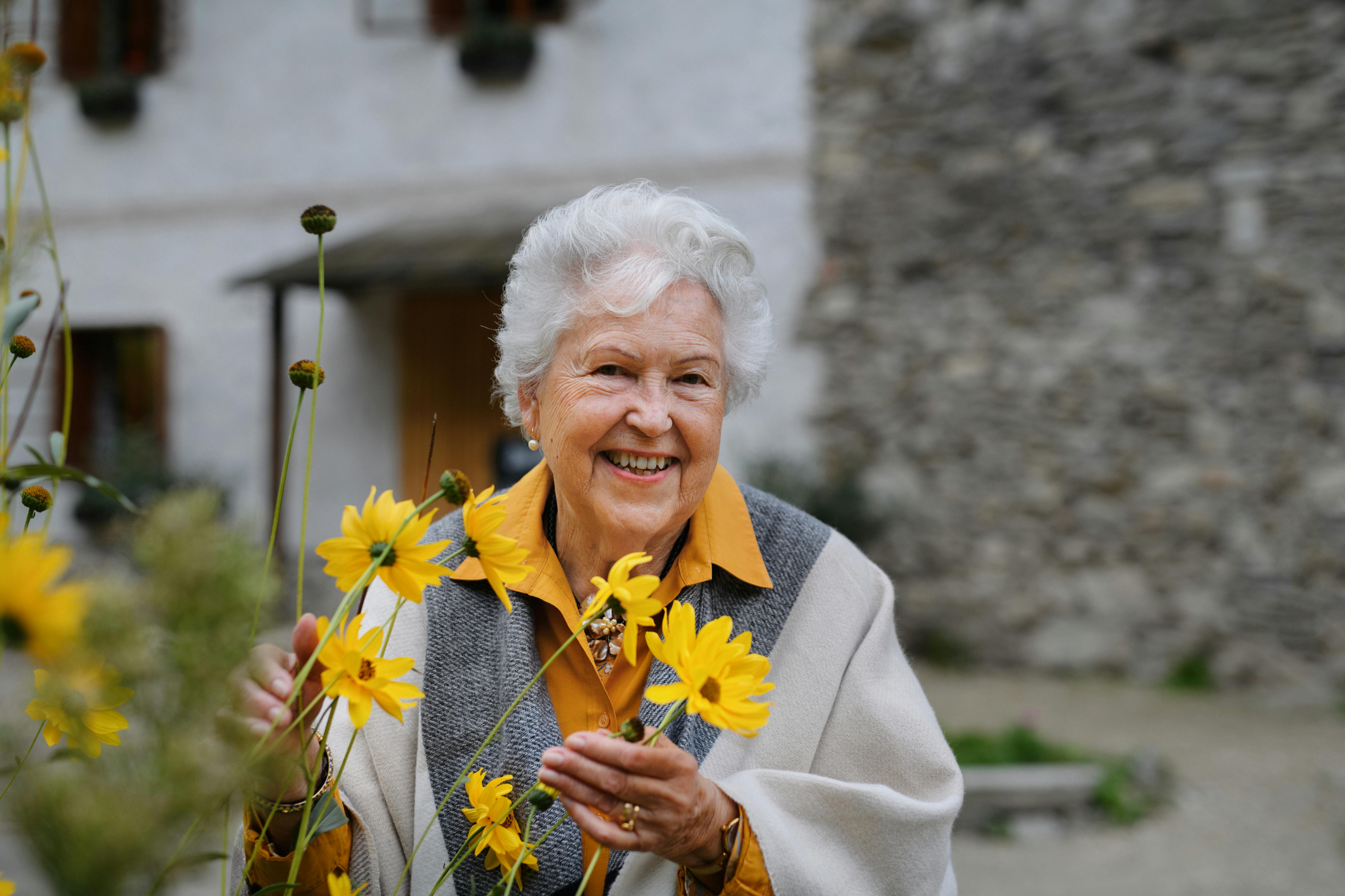 glad, ældre kvinde, der holder nogle blomster