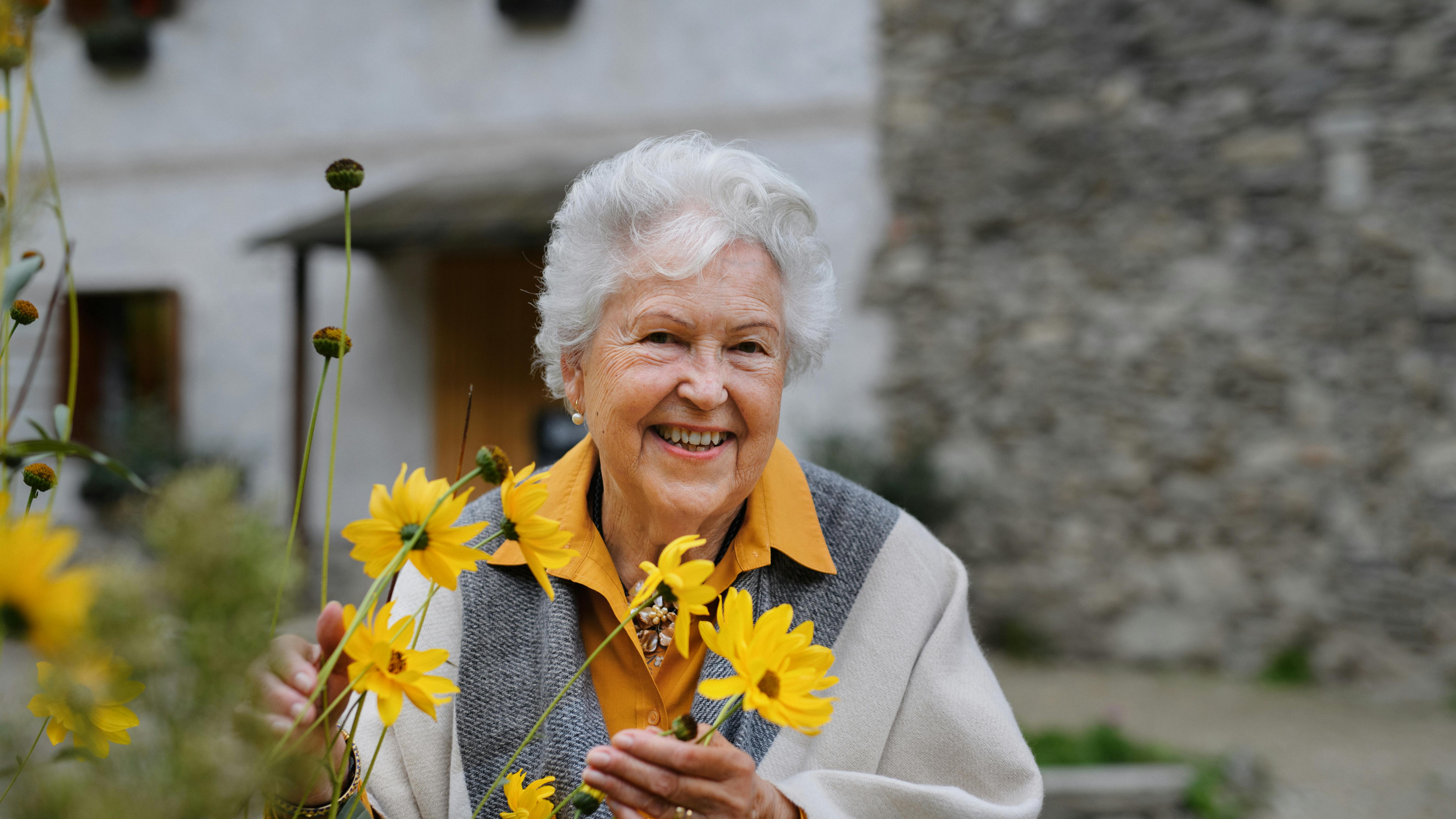 glad, ældre kvinde, der holder nogle blomster