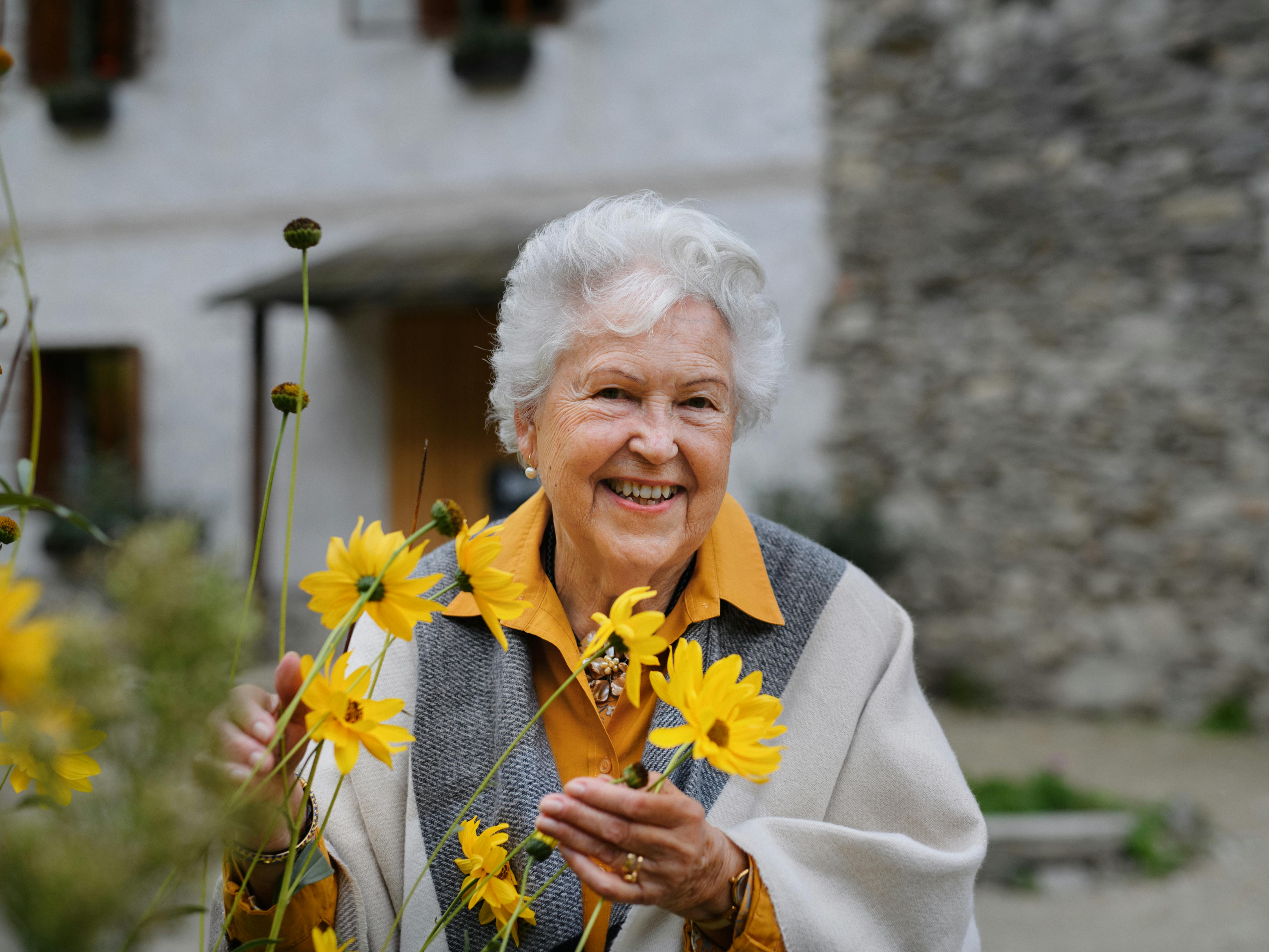 glad, ældre kvinde, der holder nogle blomster