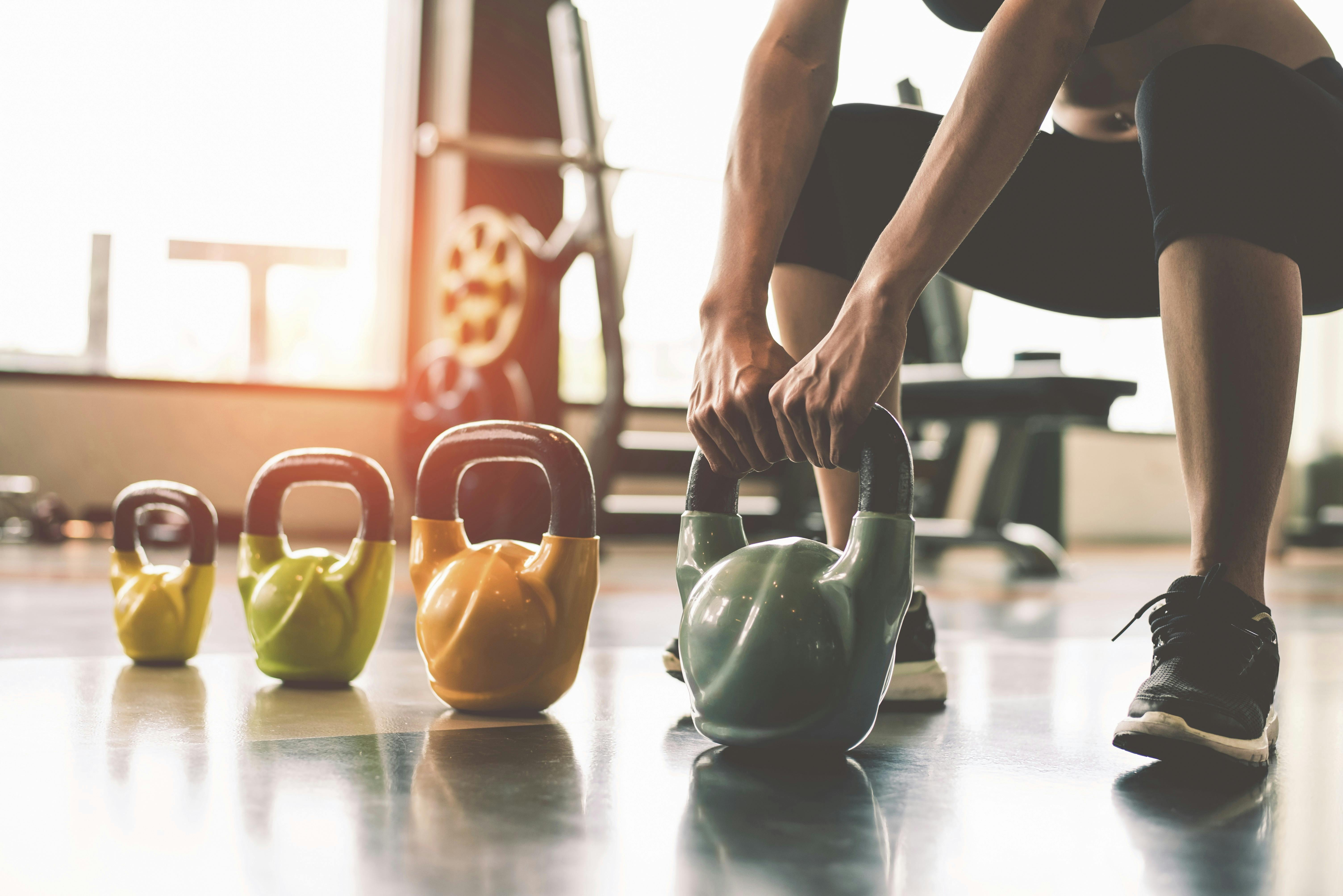 Kvinde, der styrketræner ved at løfte en kettlebell