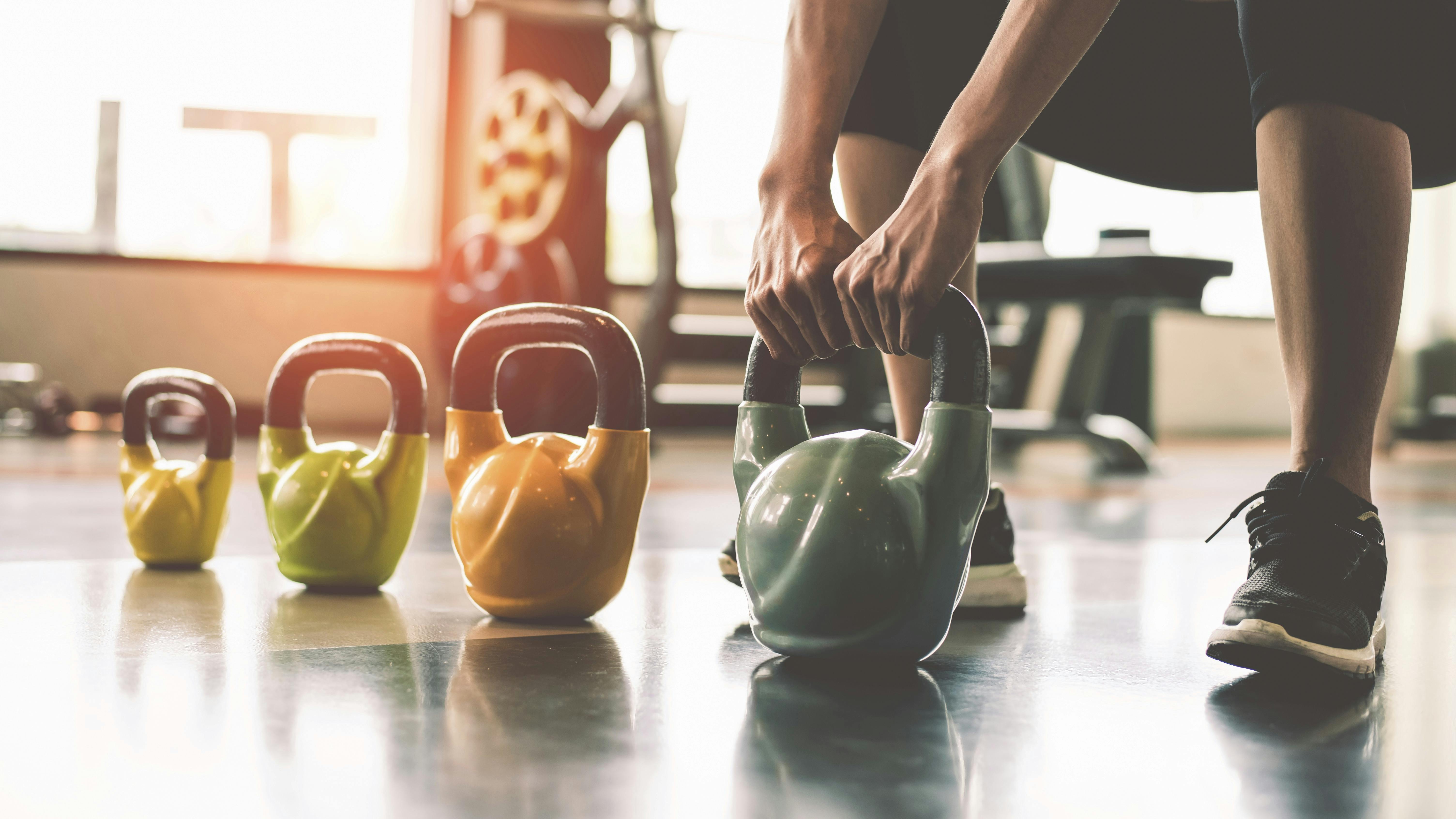 Kvinde, der styrketræner ved at løfte en kettlebell