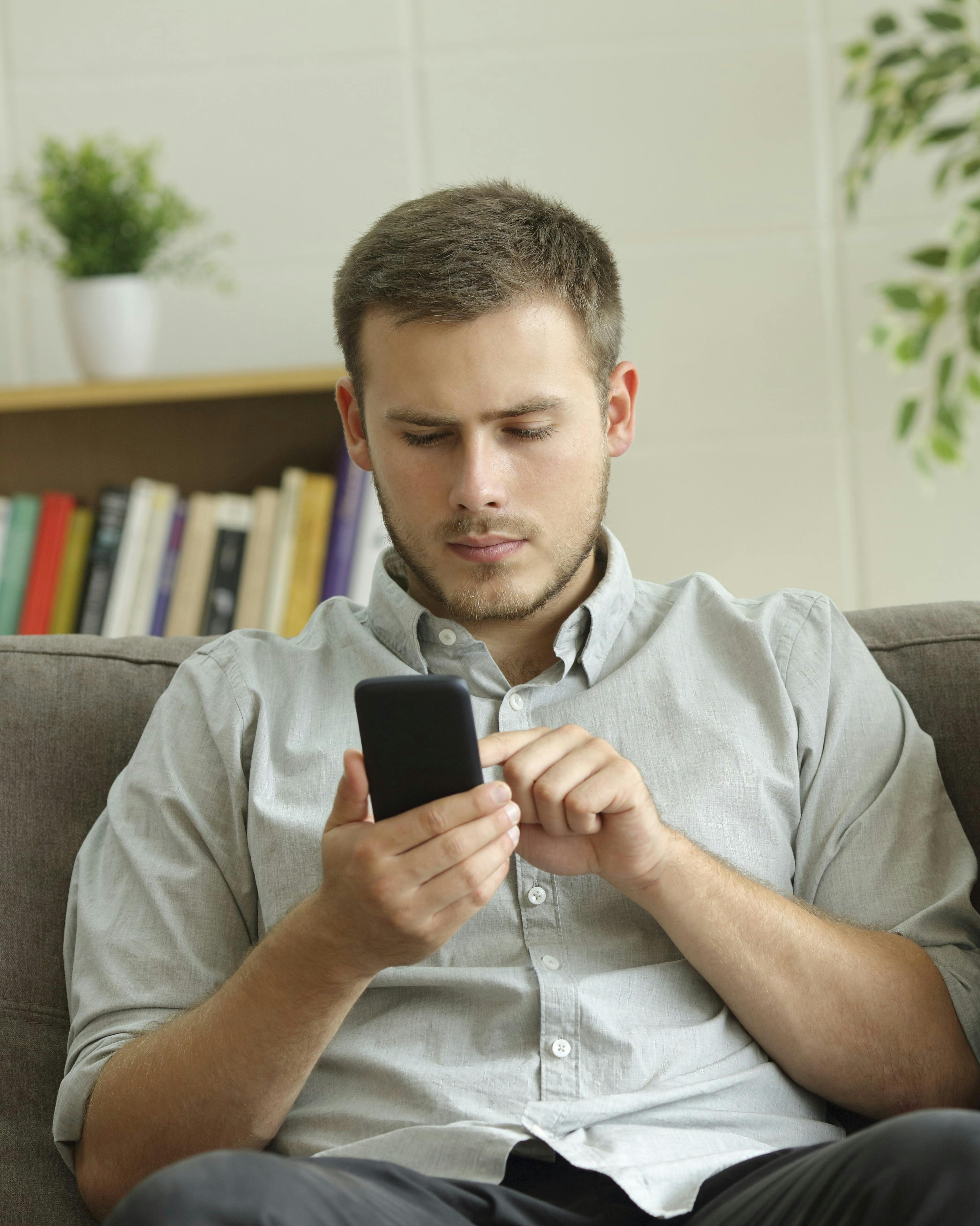 Mand kigger på sin telefon, mens konen sidder ved siden af