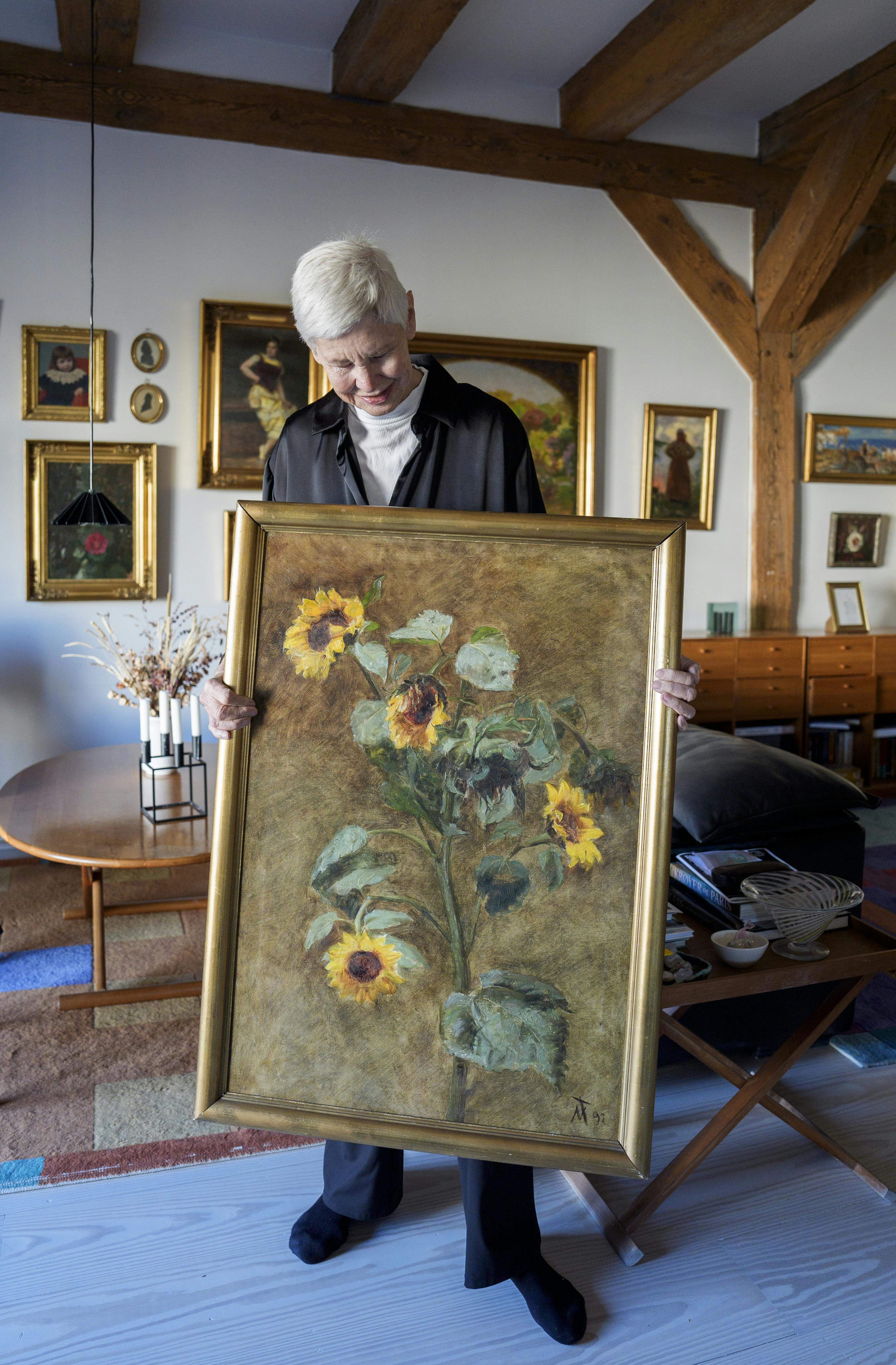 Marianne Abrahamsen med et kunstværk malet af slægtningen Nicoline Tuxen, som viser, at den talentfulde, kvindelige kunstner eksperimenterede med blomstermaleriet i takt med tidens kunstneriske strømninger.