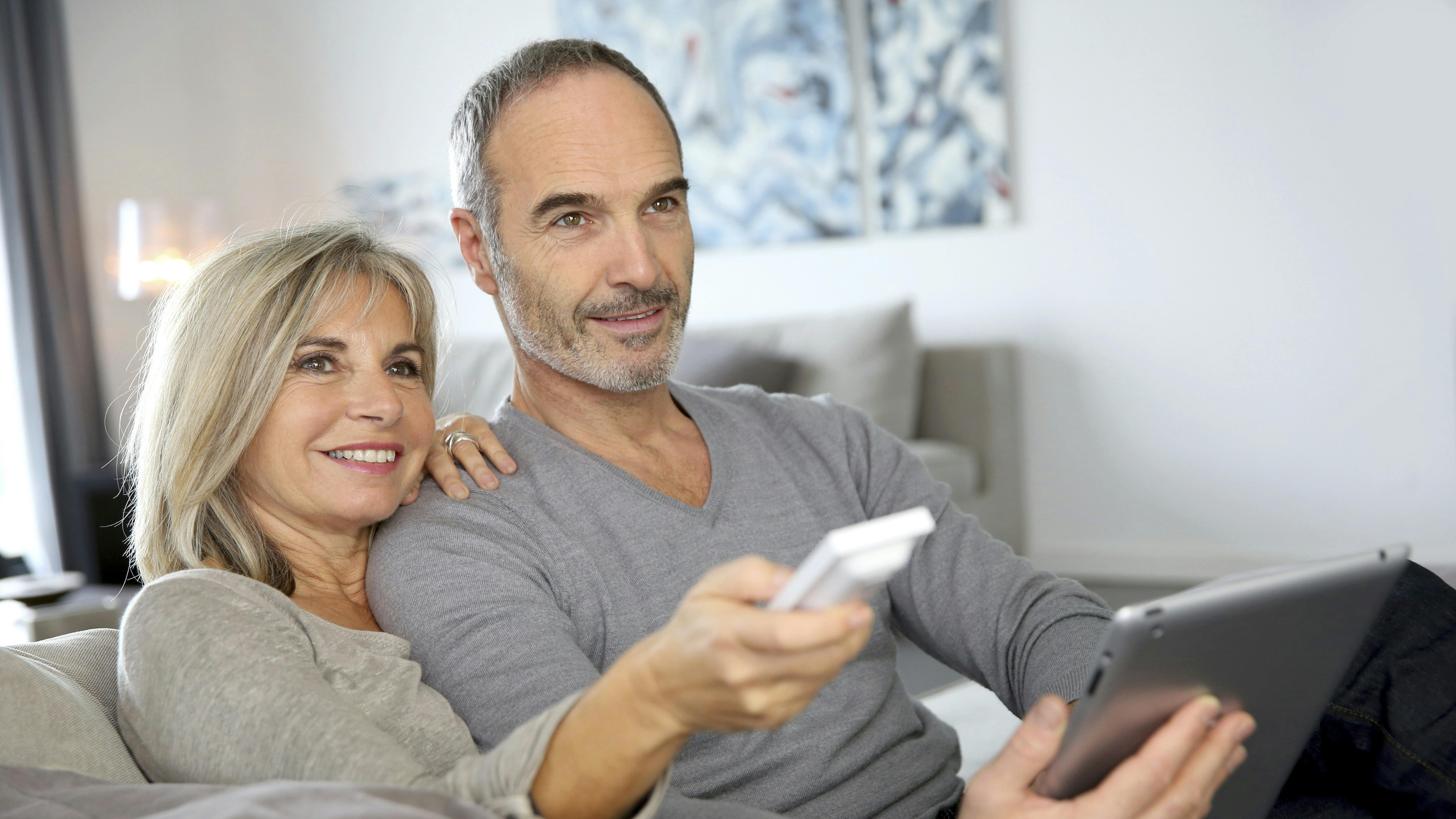 Par, der sidder i sofa og ser tv