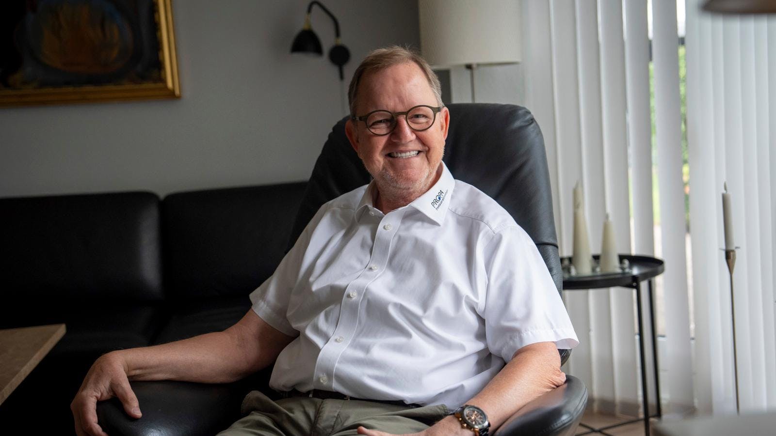 Mand sidder i lænestol og smiler