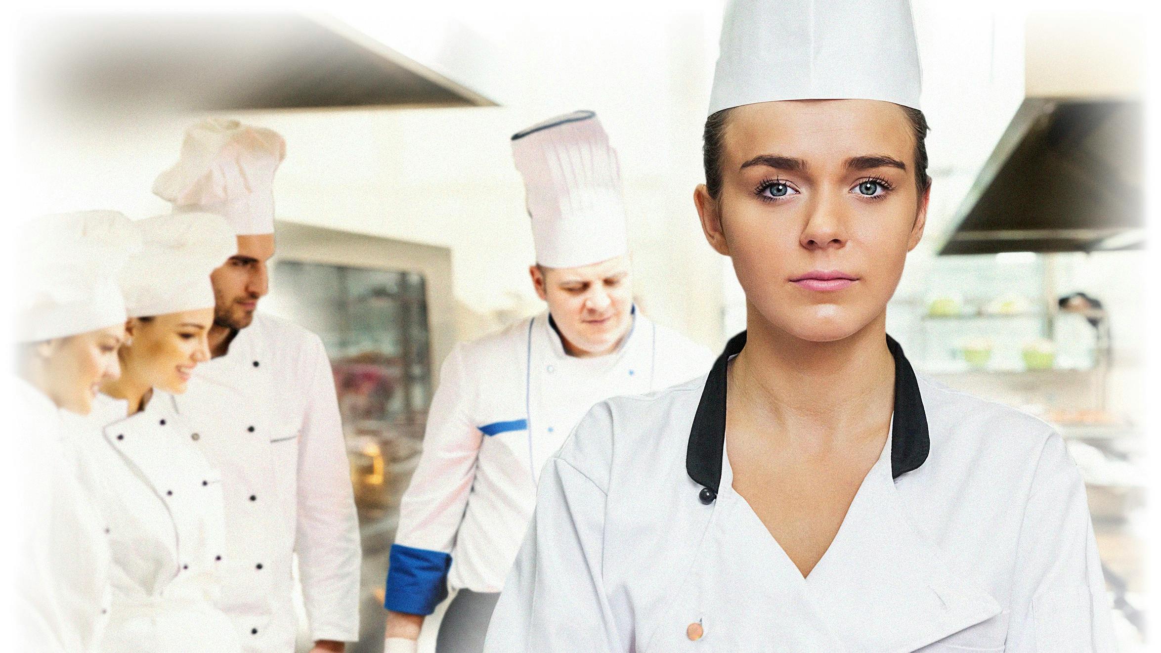 Ung kvinde i kokkeuniform med kokke i baggrunden