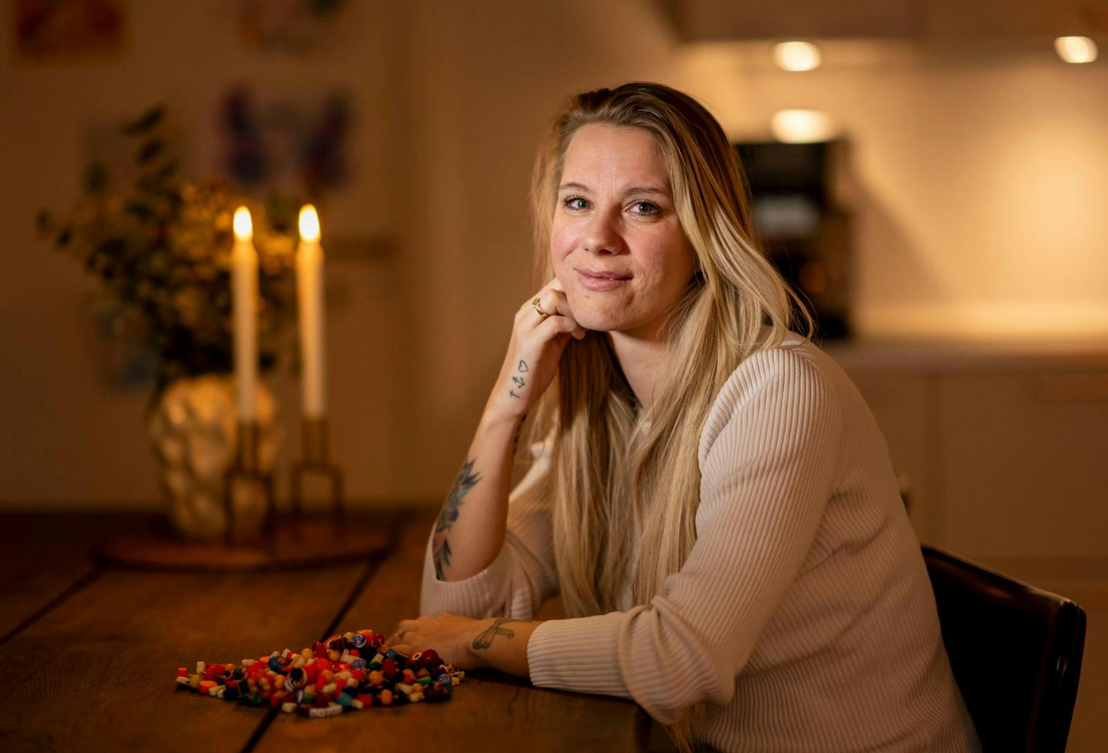 Kvinde sidder ved bord og smiler forsigtigt