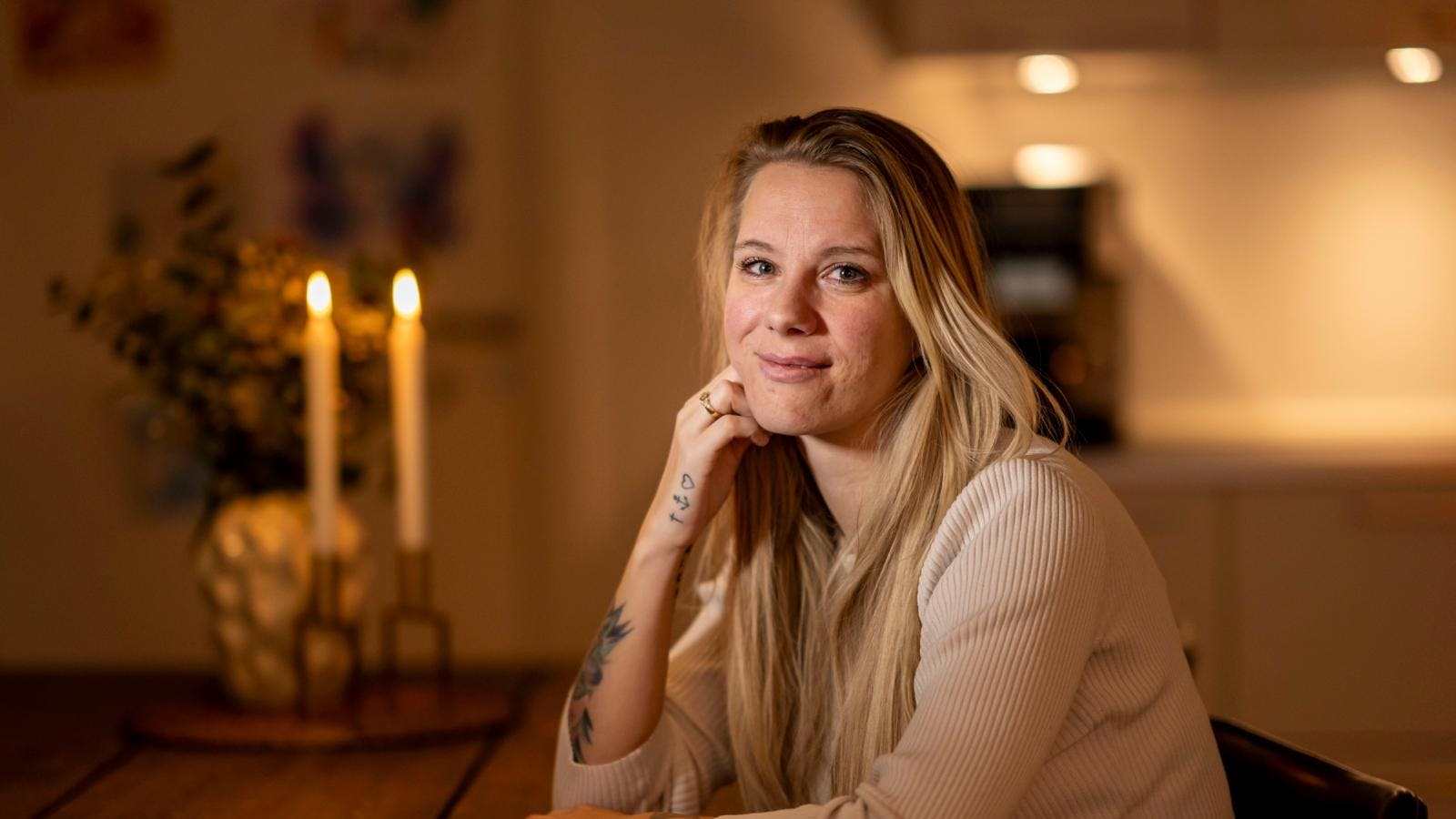 Kvinde sidder ved bord og smiler forsigtigt