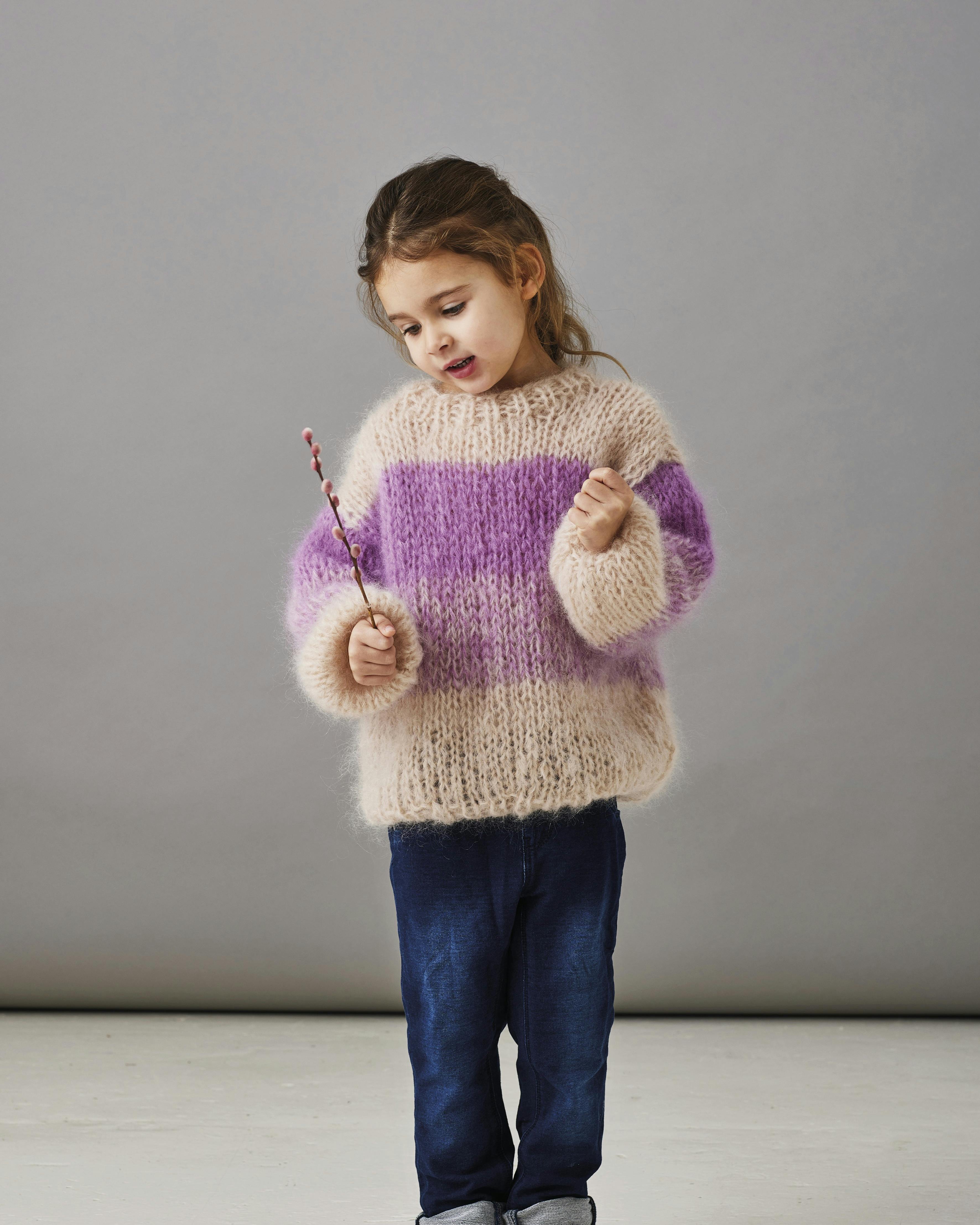 Sweater med brede striber, hvor pigen der har den på kigger ned i jorden.