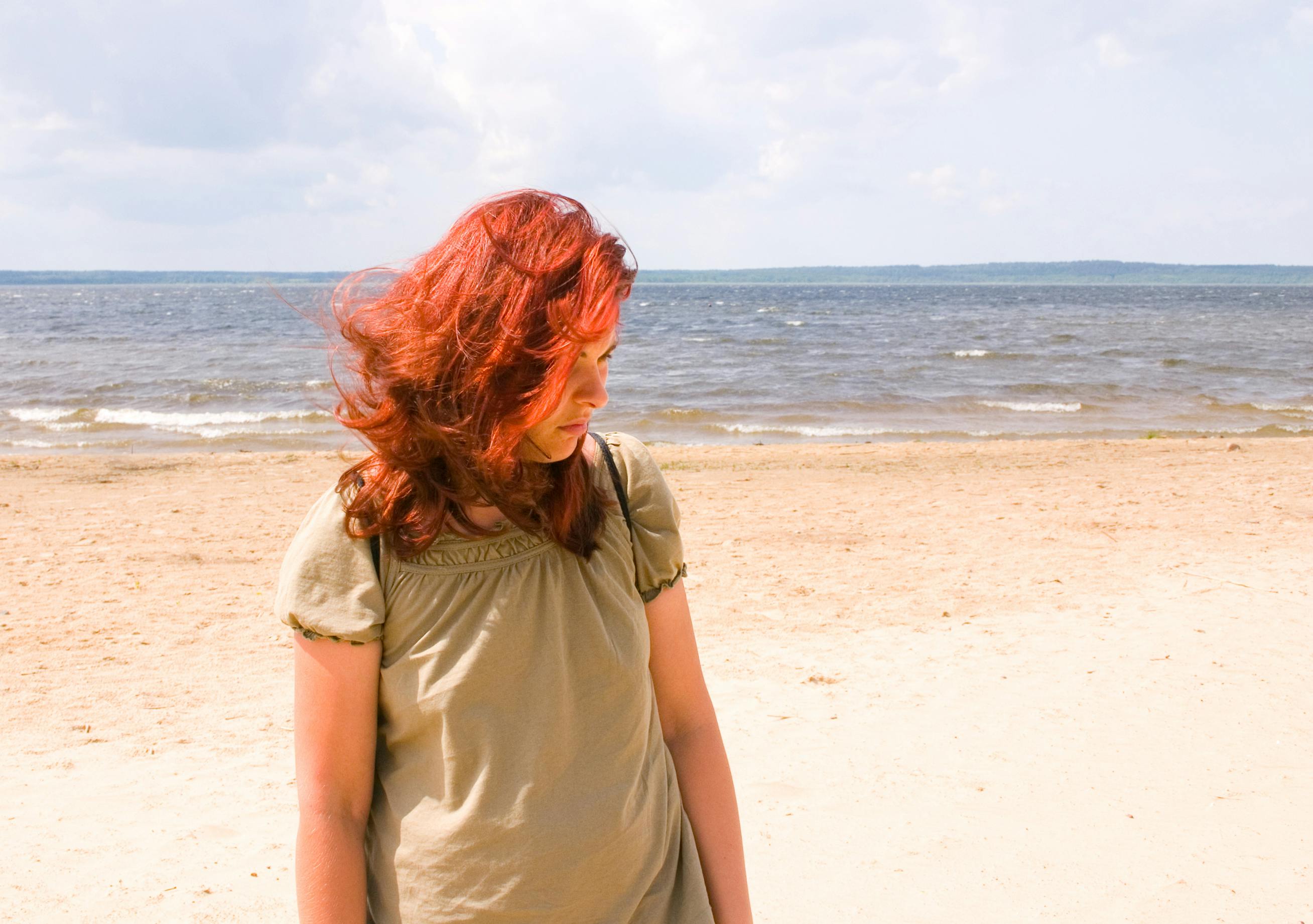 rødhåret kvinde på strand, der er ked af det