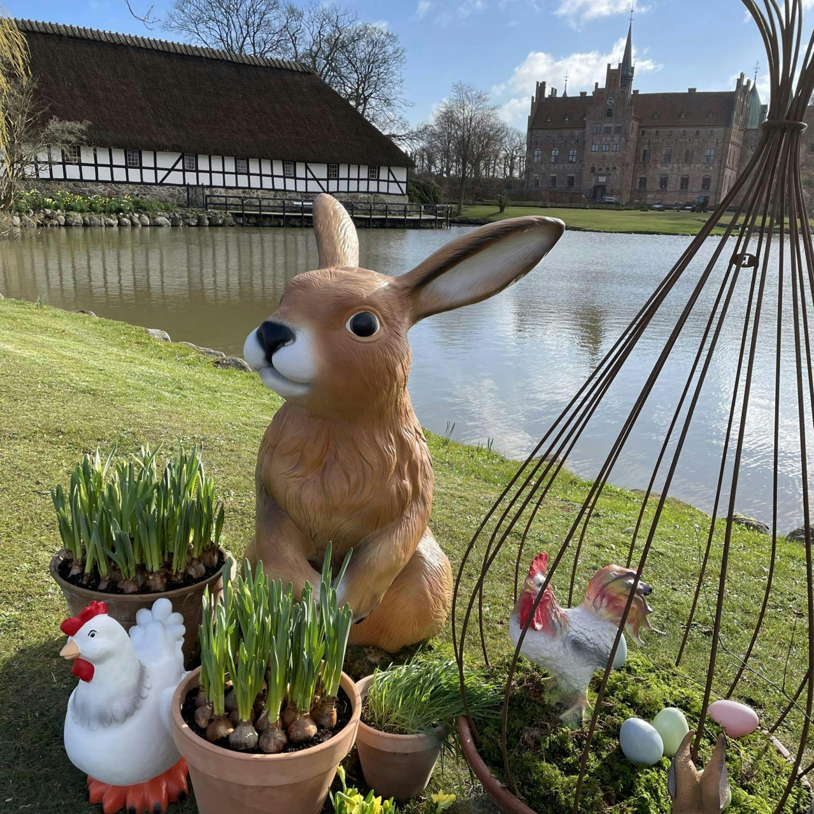 Stor påskehare og løgplanter i krukke samt pyntehøns og æg.
