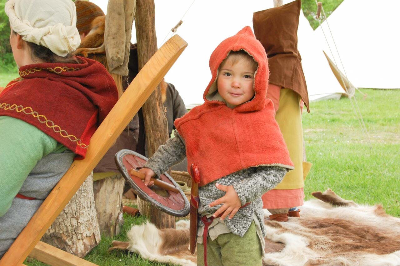 Lille dreng, der er klædt ud i tøj fra jernalderen