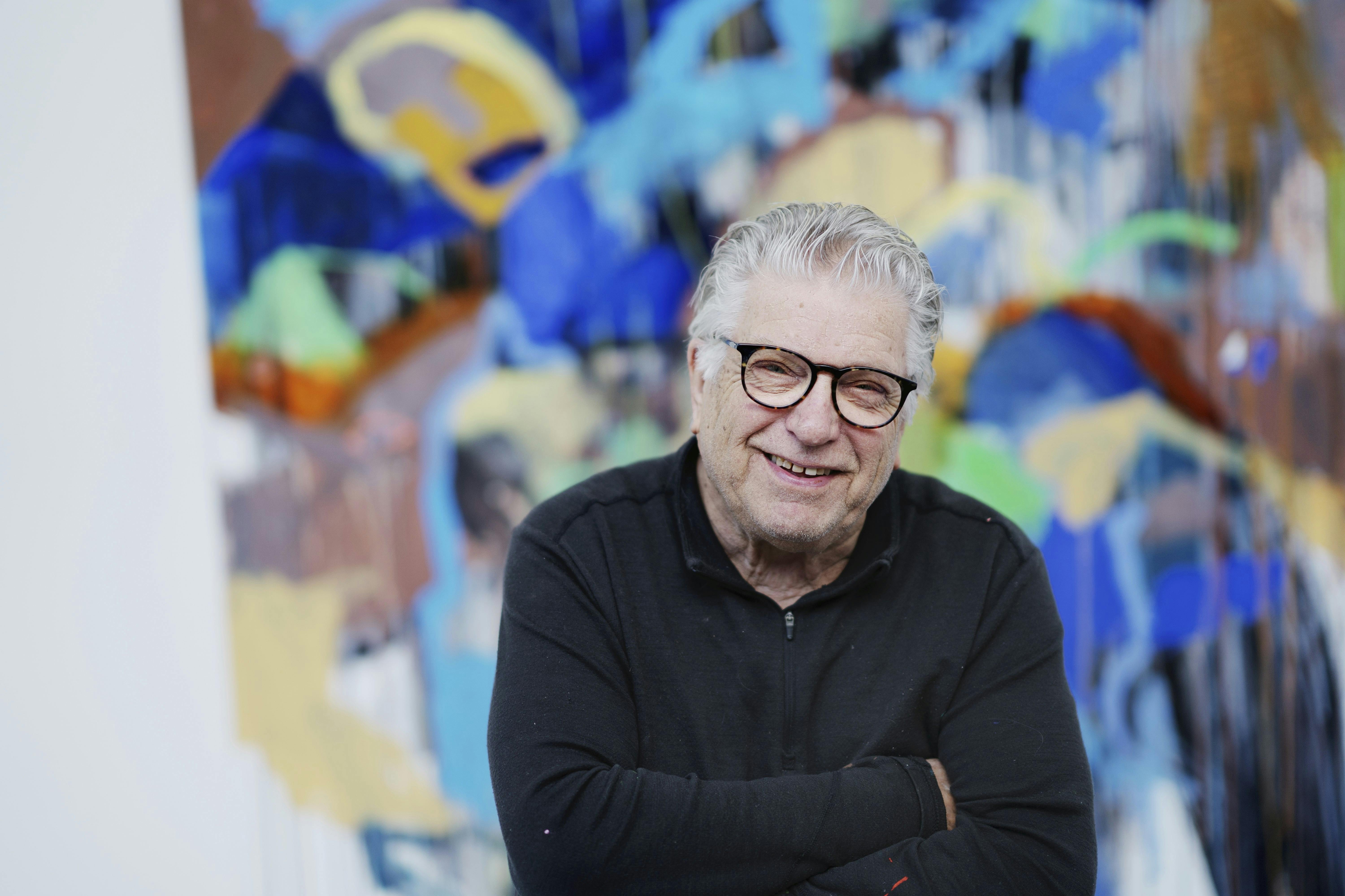 Multikunstneren Leif Sylvester foran et af sine mange farverige malerier.