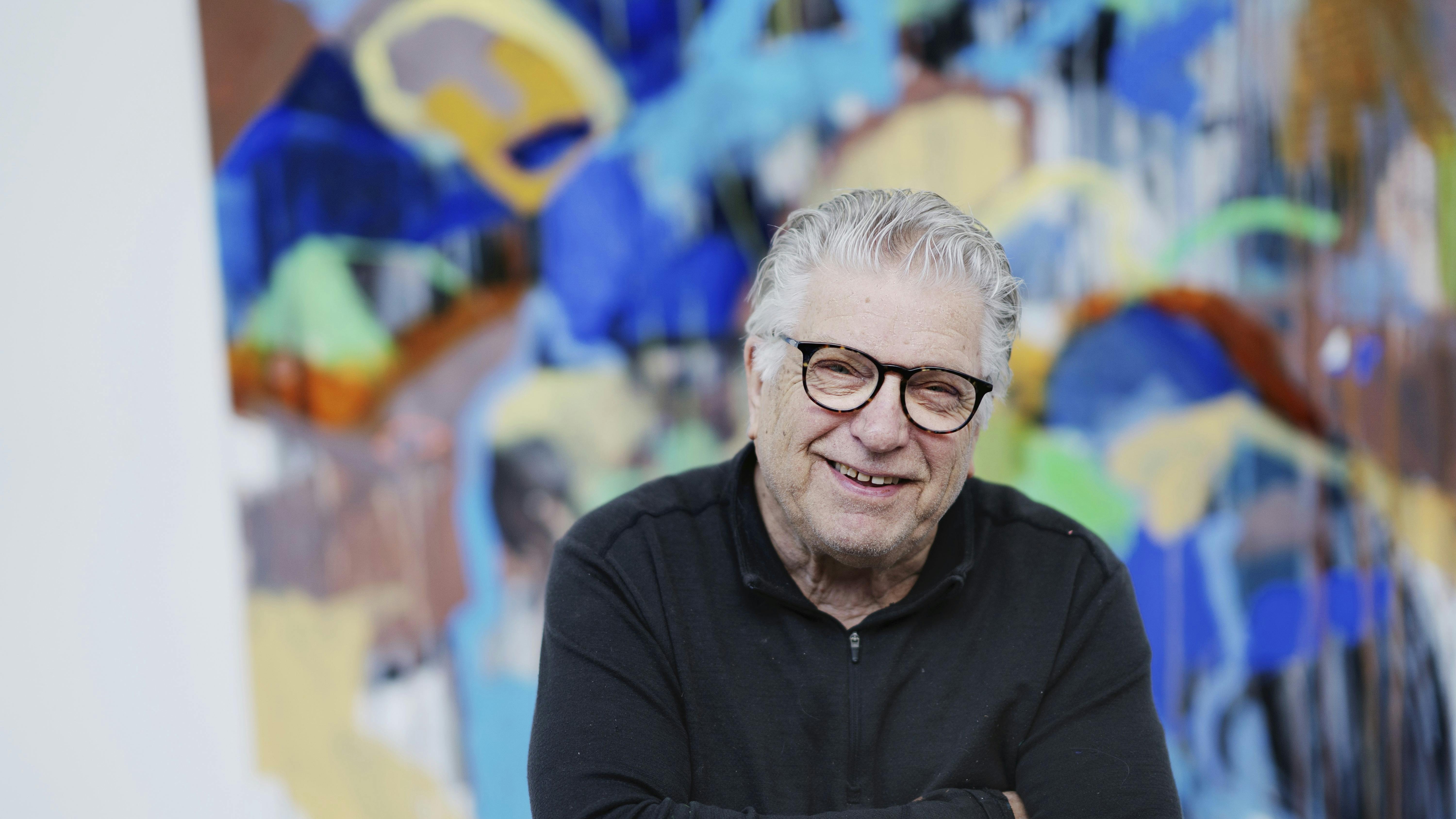 Multikunstneren Leif Sylvester foran et af sine mange farverige malerier.
