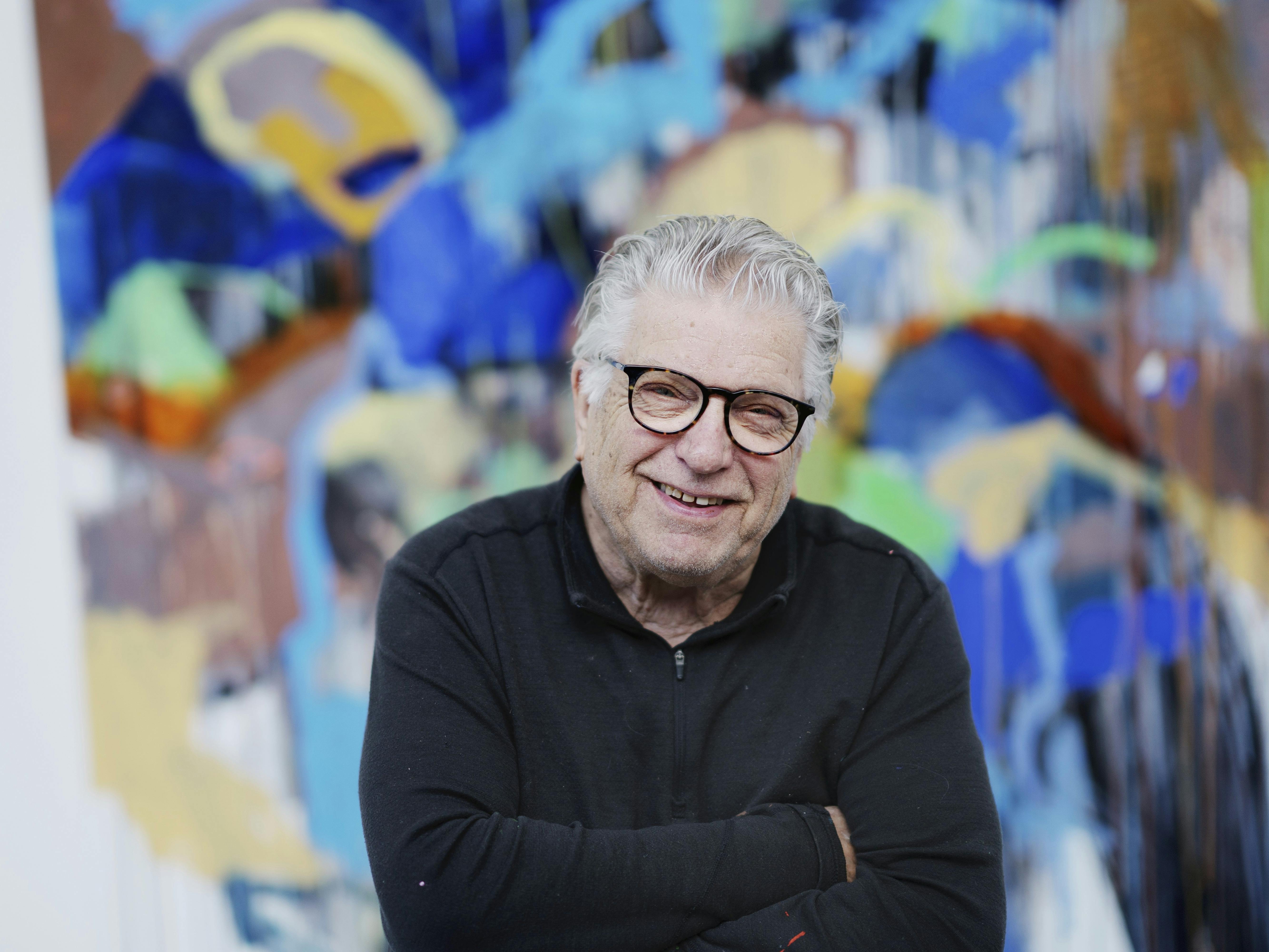 Multikunstneren Leif Sylvester foran et af sine mange farverige malerier.