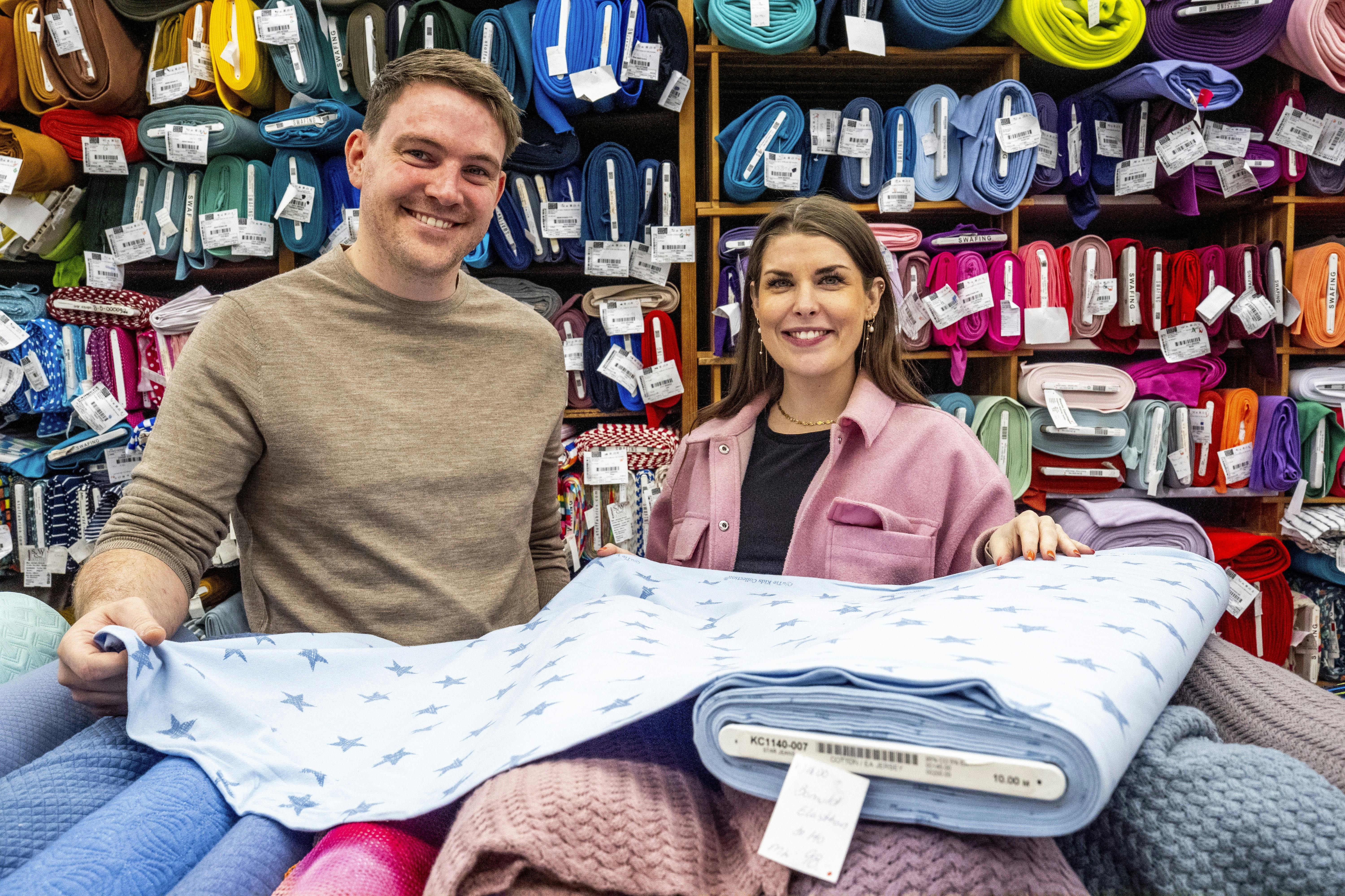 Anders Ingwersen og Emilie Lindevang fra 2024-sæsonen af datingprogrammet kigger på lyseblåt babystof i Anders' forældres butik, Stofmøllen.