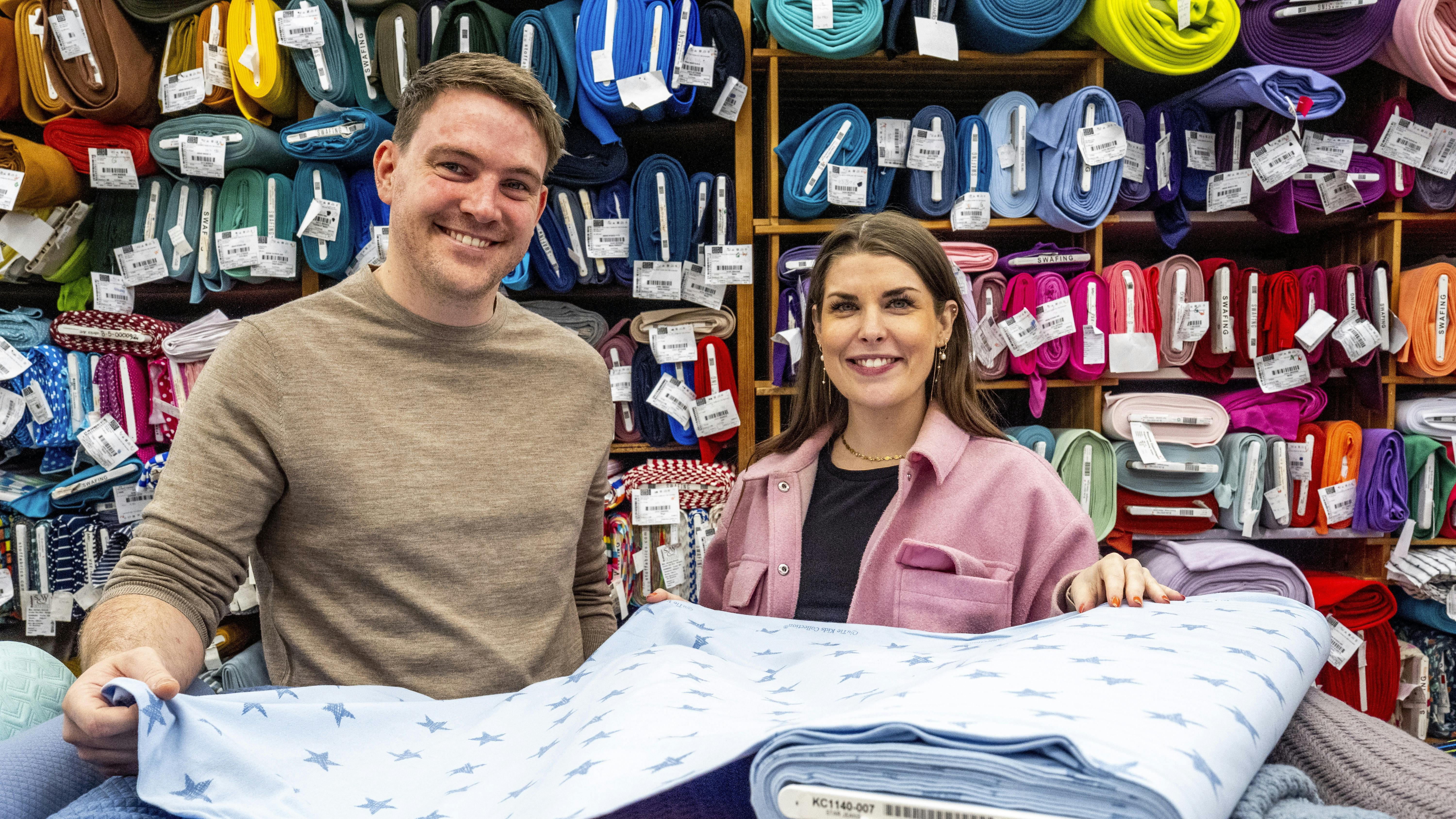Anders Ingwersen og Emilie Lindevang fra 2024-sæsonen af datingprogrammet kigger på lyseblåt babystof i Anders' forældres butik, Stofmøllen.