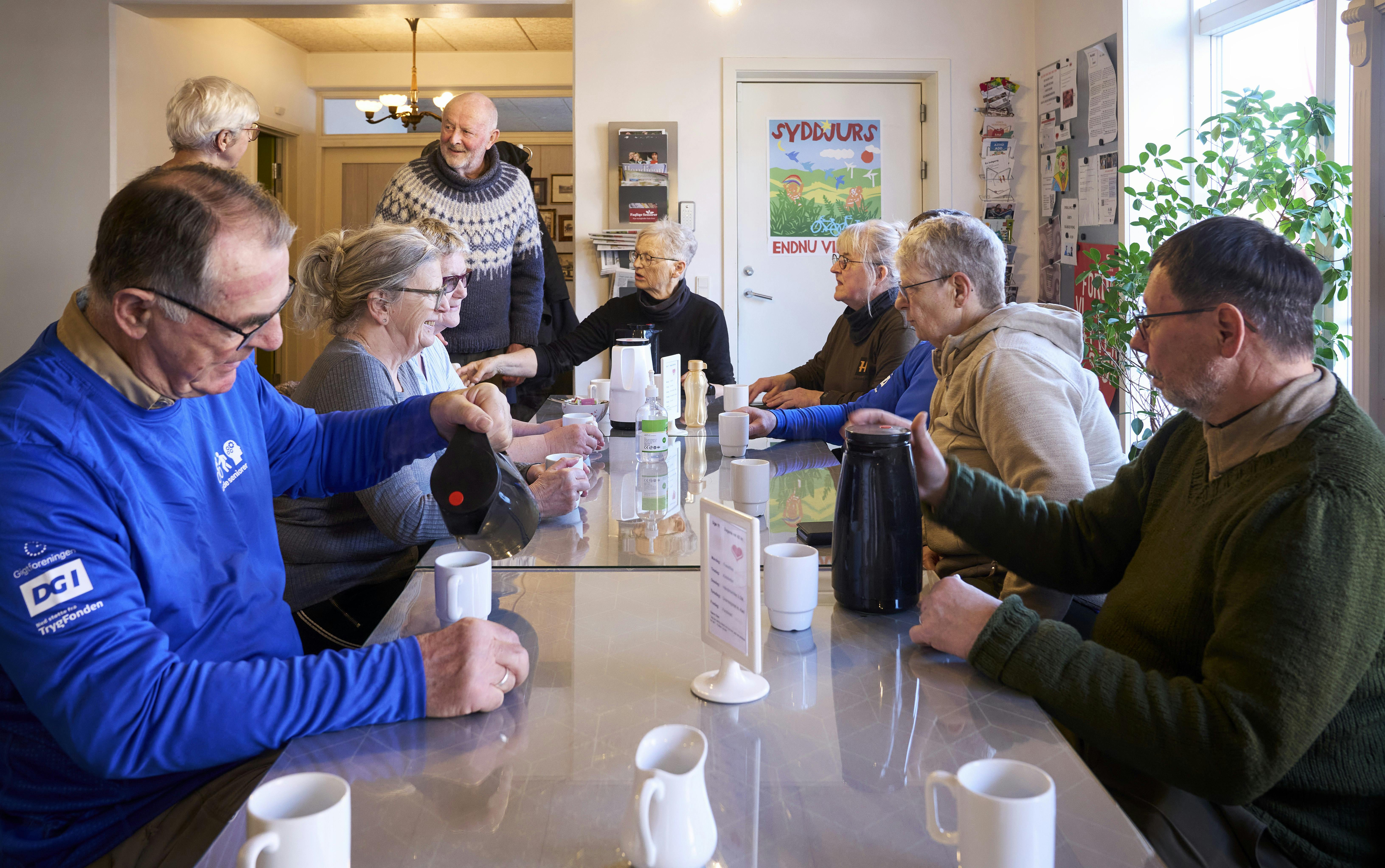 Gruppen og sidder, og drikker kaffe på en cafe.