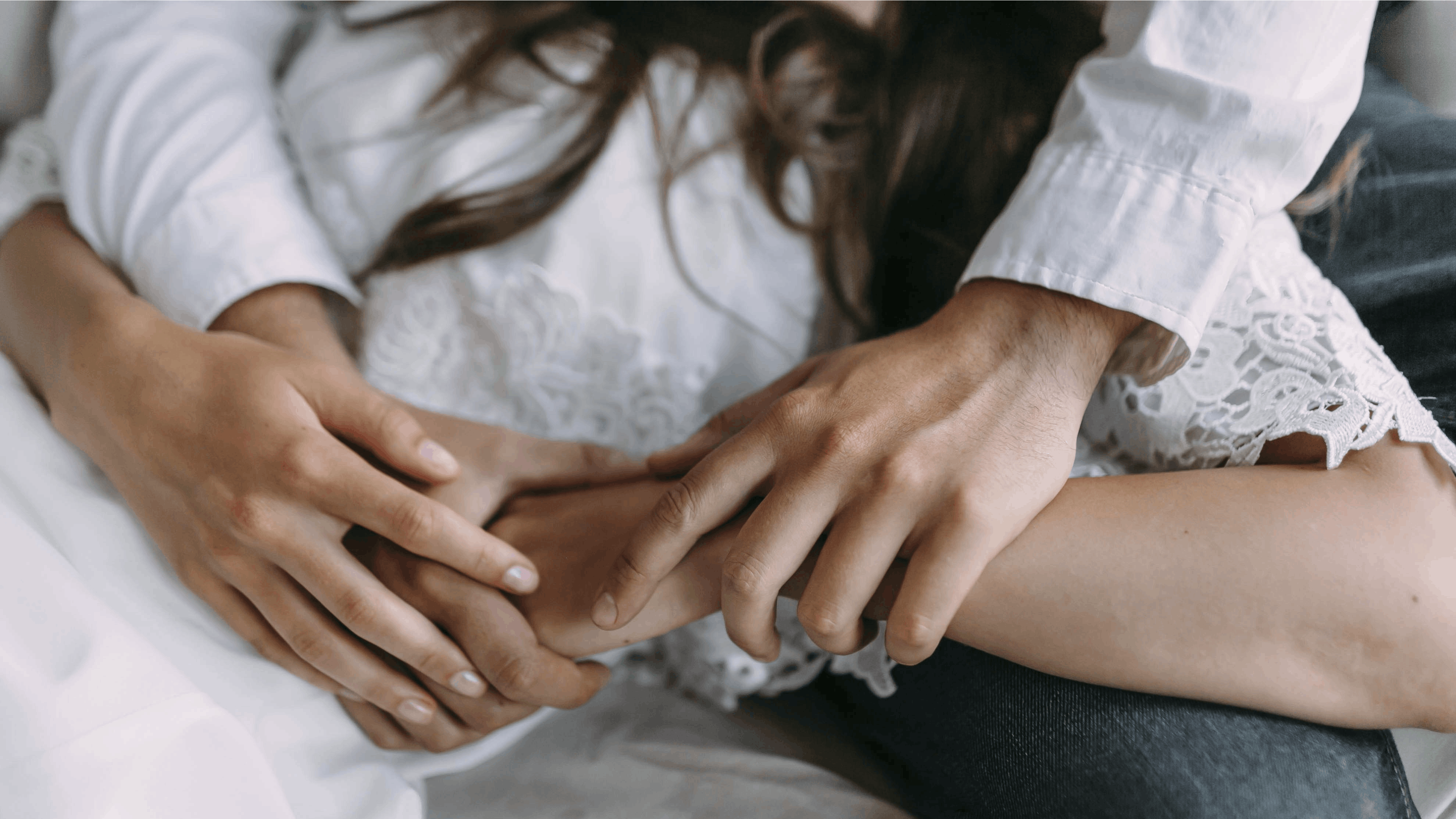 Par kærtegner hinandens hænder.