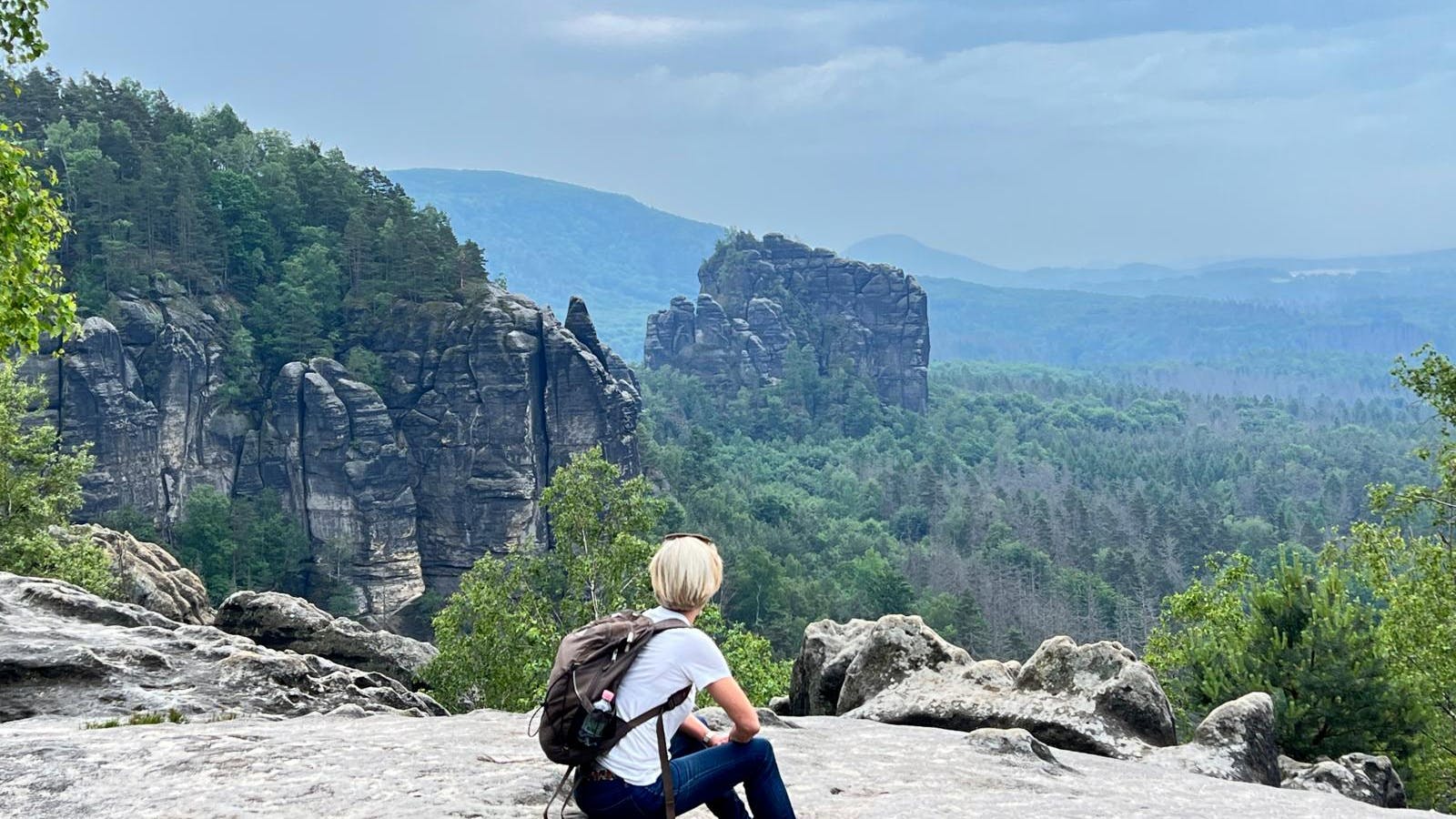 Kvinde sidder på et bjerg og nyder udsigten